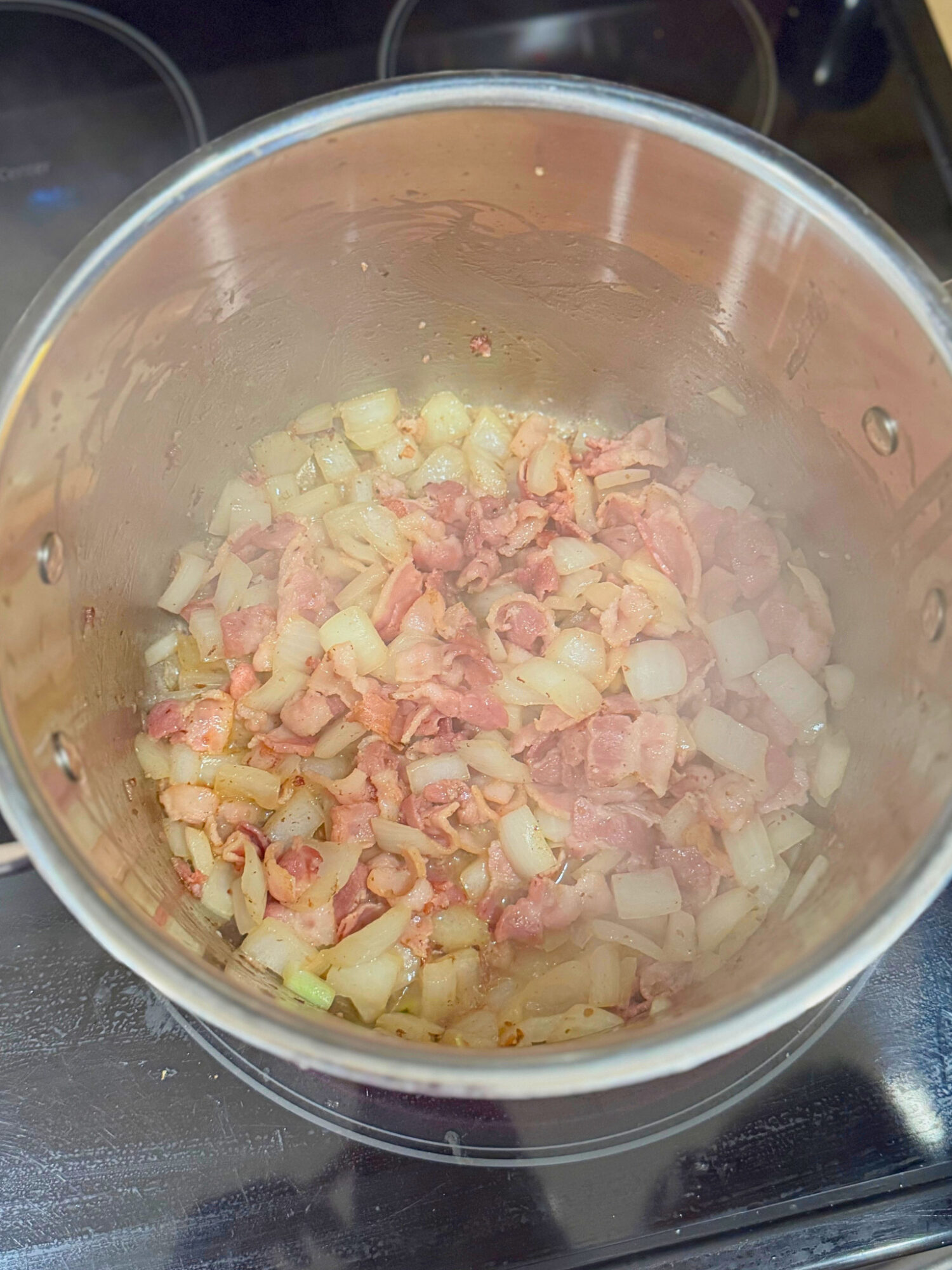 Crispy bacon and onion simmering in a large pot.