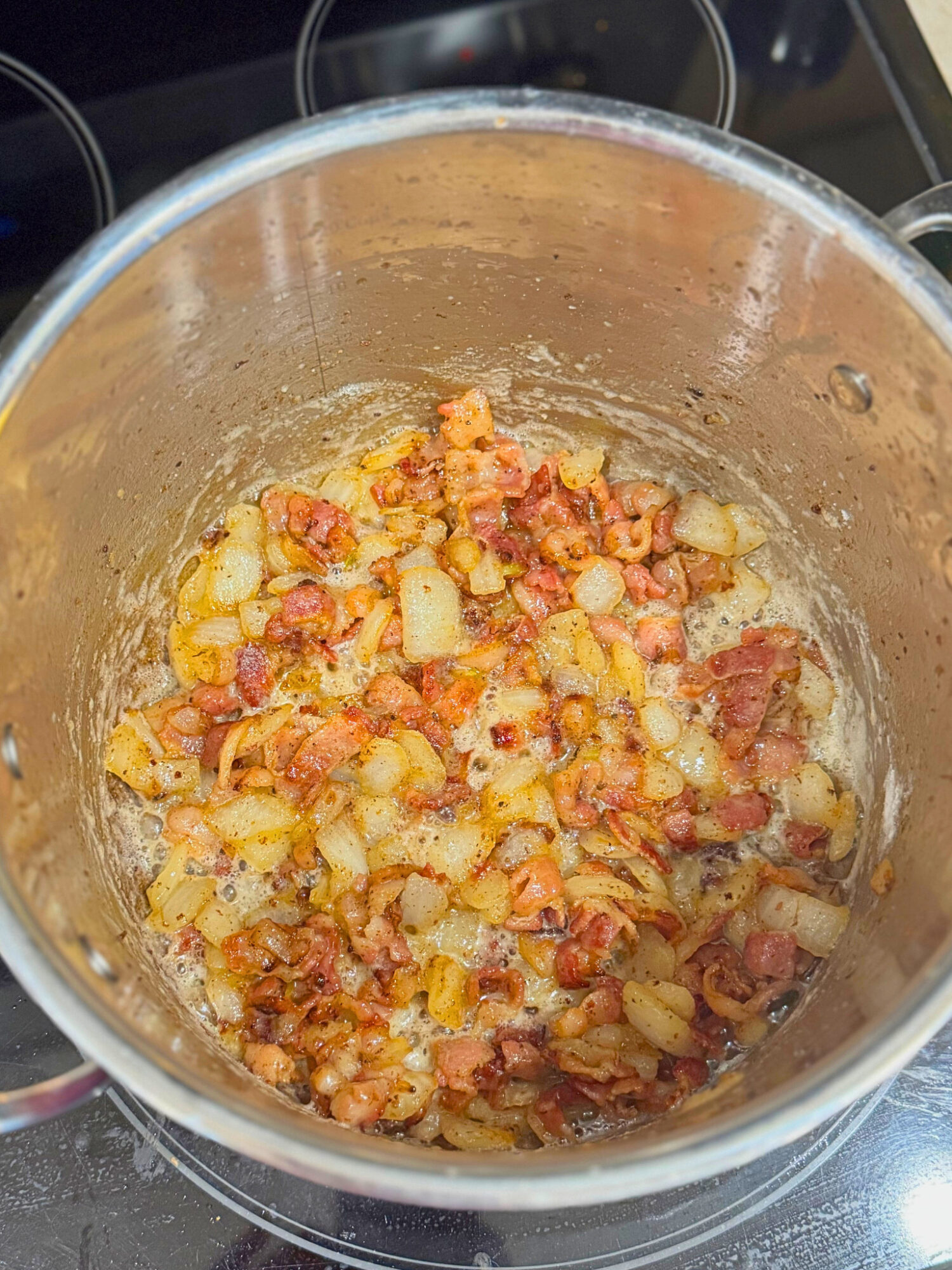 Crispy bacon and onion in a large pot over the stove.