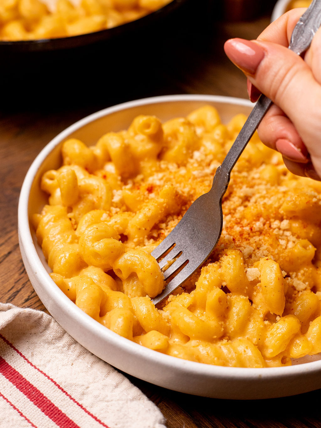 Dipping a fork into mac and cheese with breadcrumb topping.