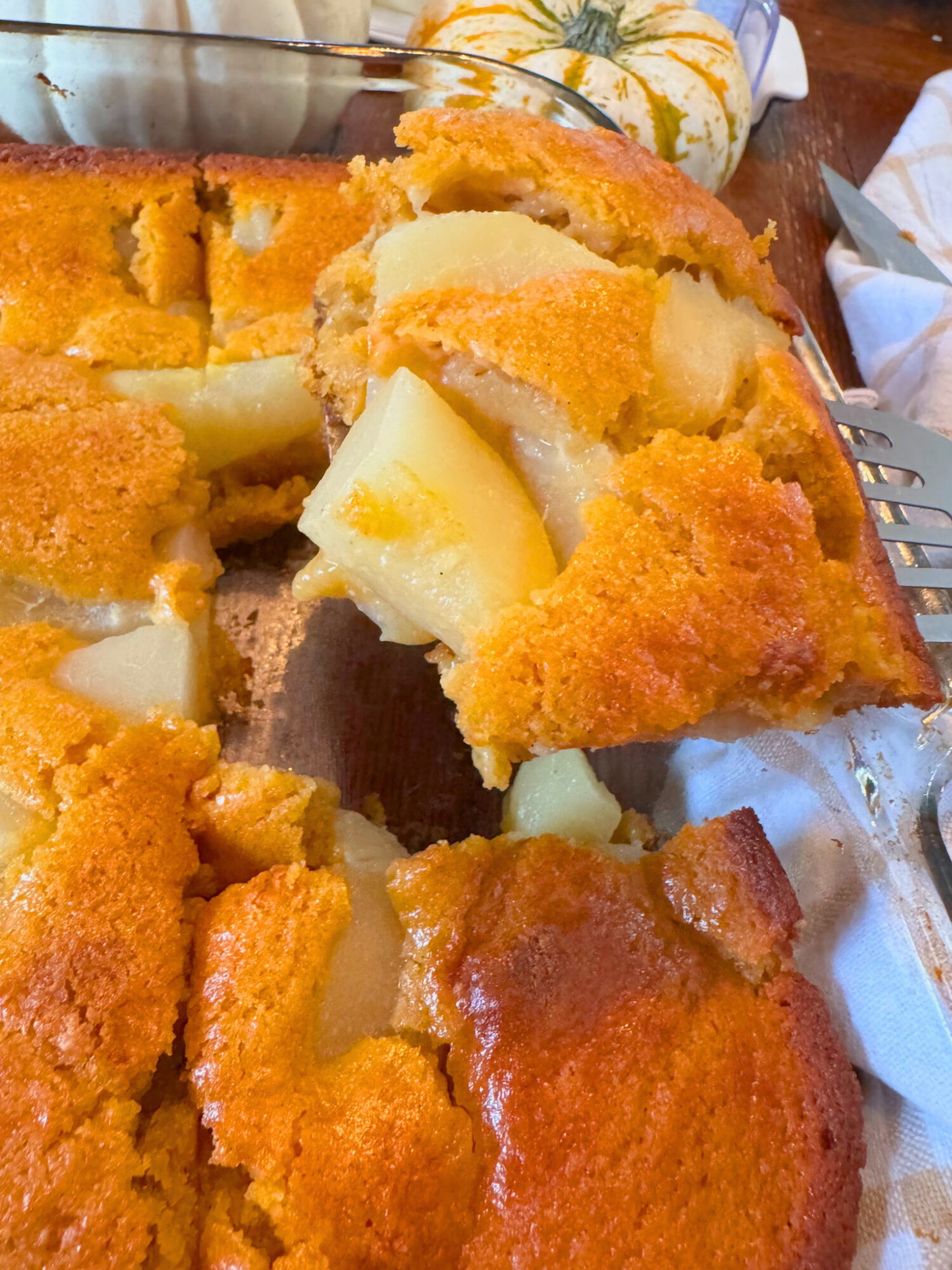 A spatula taking a piece of pumpkin pear cobbler out of a baking dish.