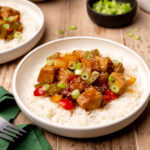 A bowl of sweet and sour pork on a bed of white rice.