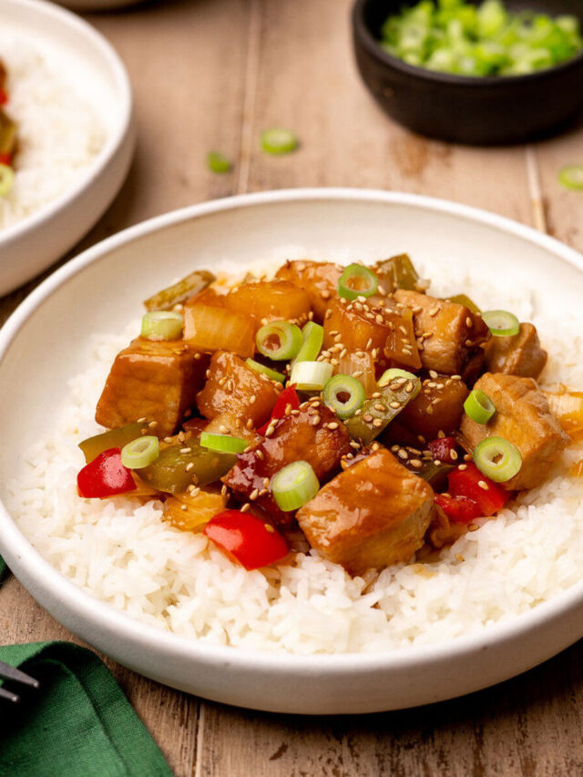 A bowl of sweet and sour pork on a bed of white rice.