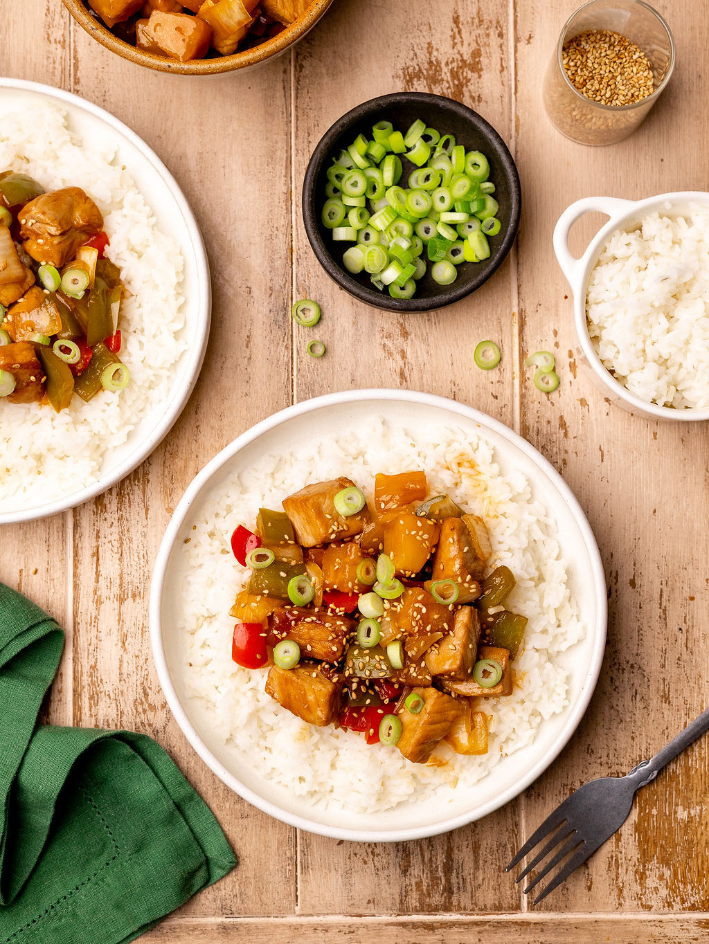 Two bowls of sweet and sour pork surrounded by ingredients.