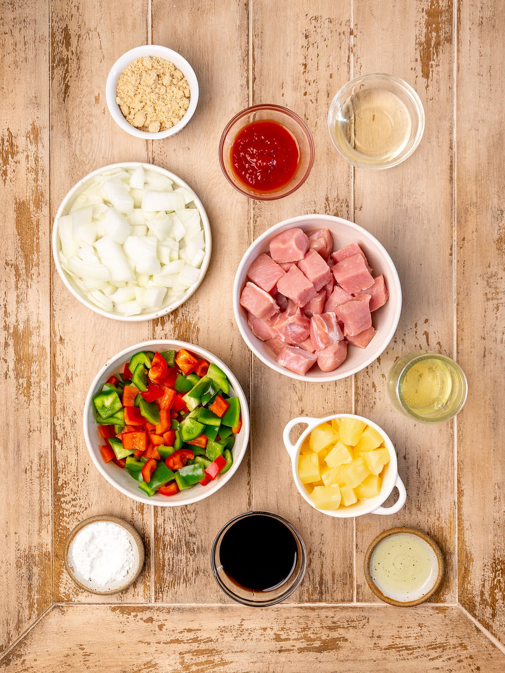 Ingredients for sweet and sour pork over a light wooden surface.