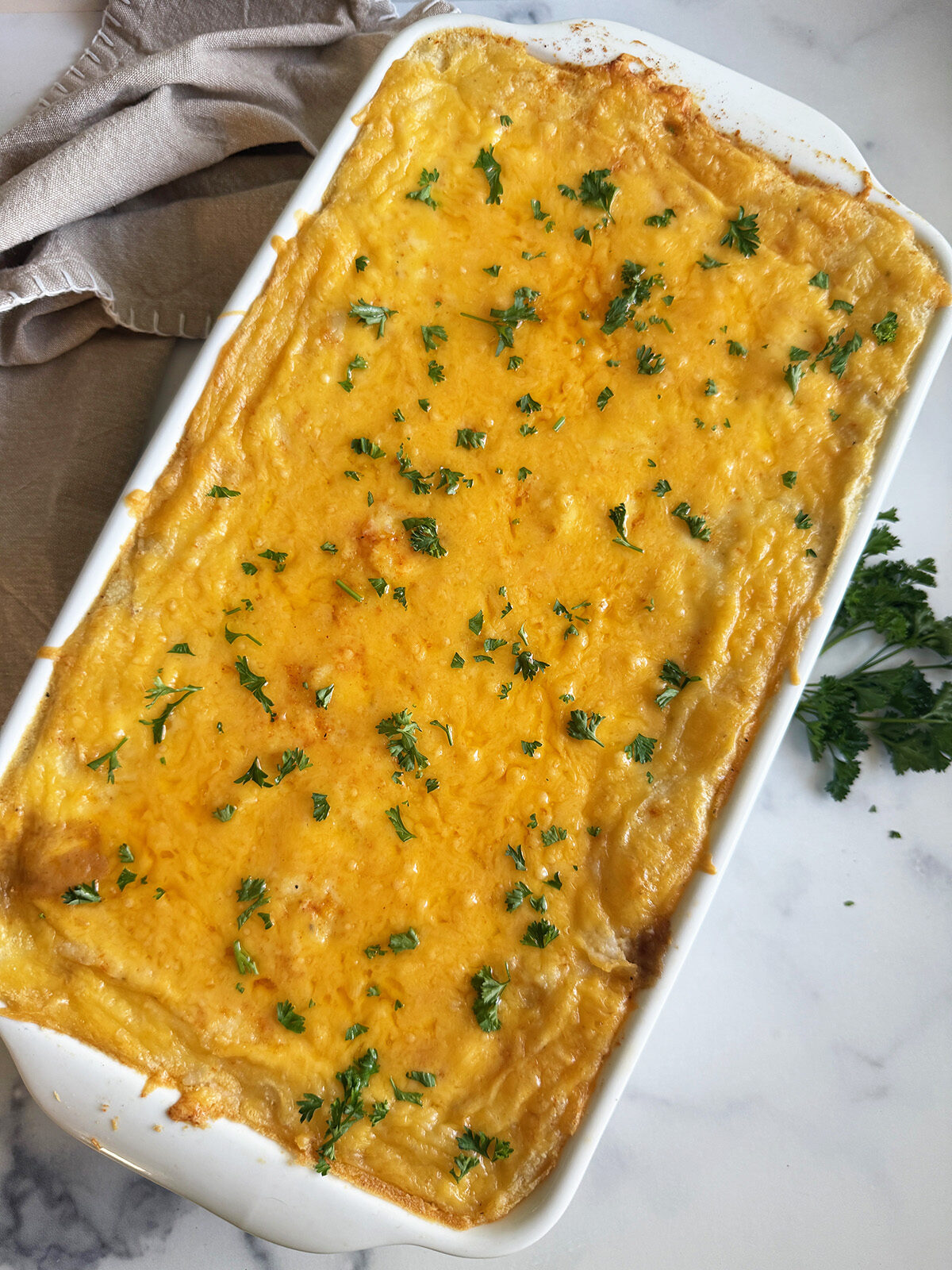 A bubbling, golden casserole filled with beef, mushrooms, green beans, and mashed potatoes under a cheesy crust.
