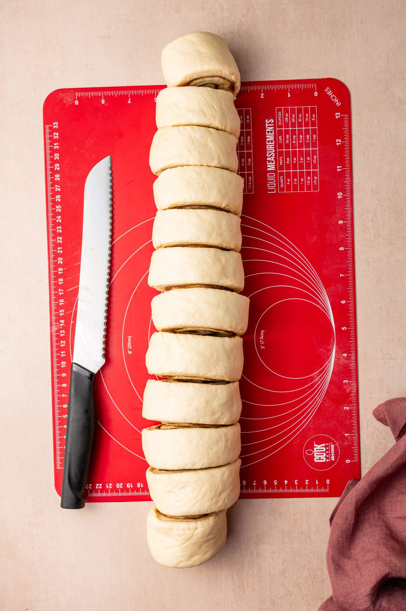 Sliced cinnamon rolls on a red cutting board.