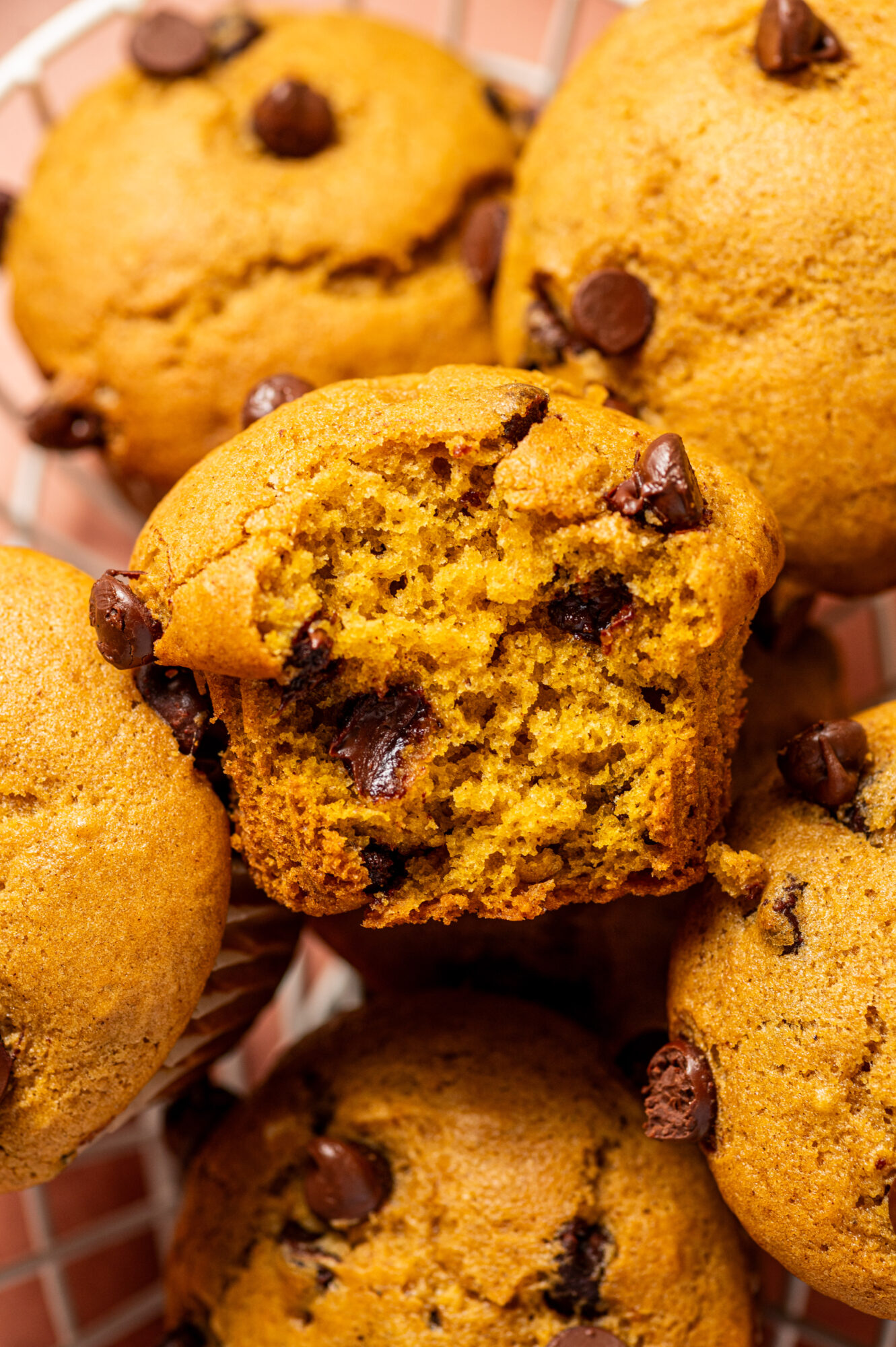 Bitten-into pumpkin muffins with chocolate chips.