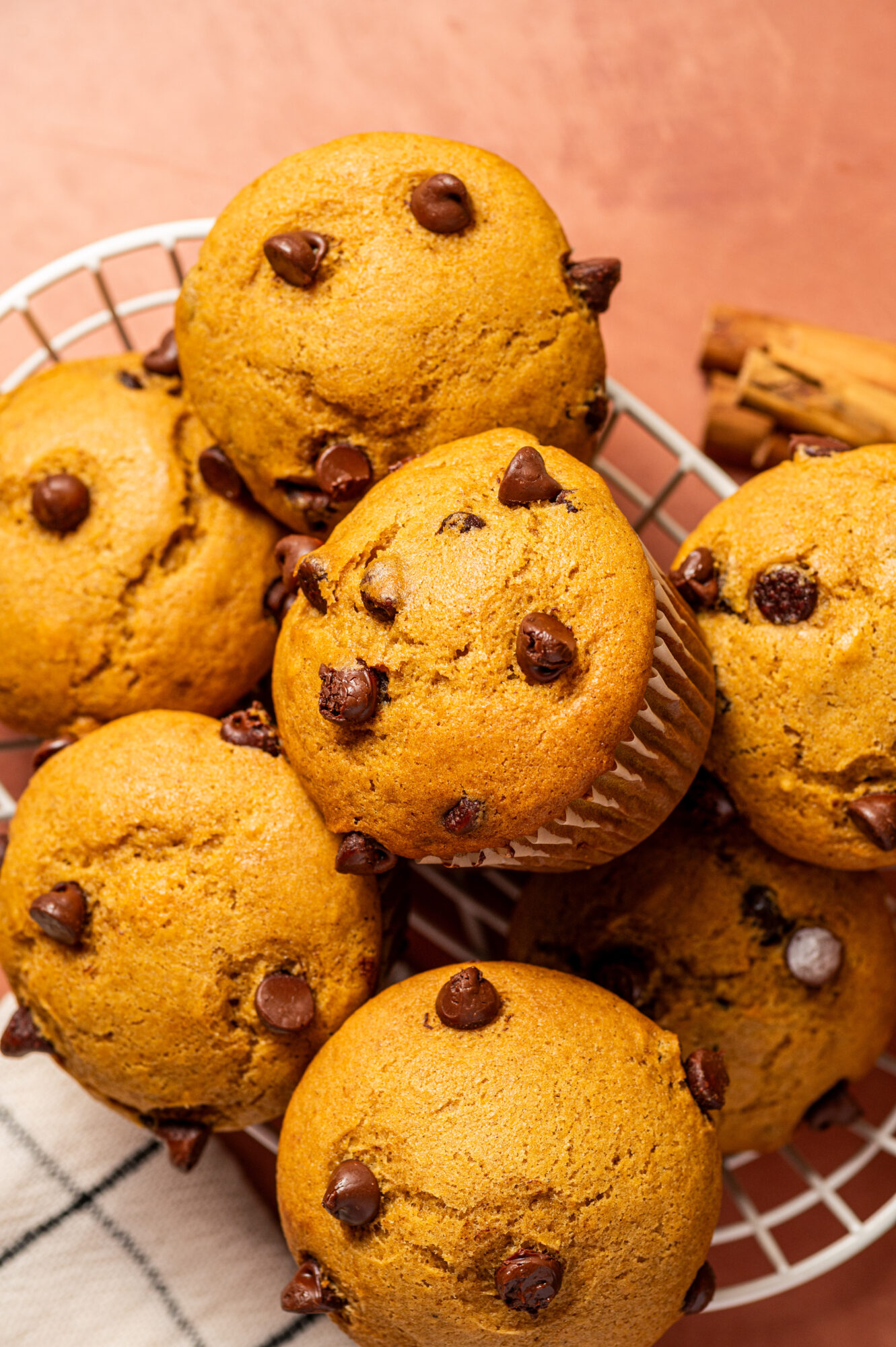 Close-up of a basket of chocolate chip and pumpkin muffins surrounded by ingredients.