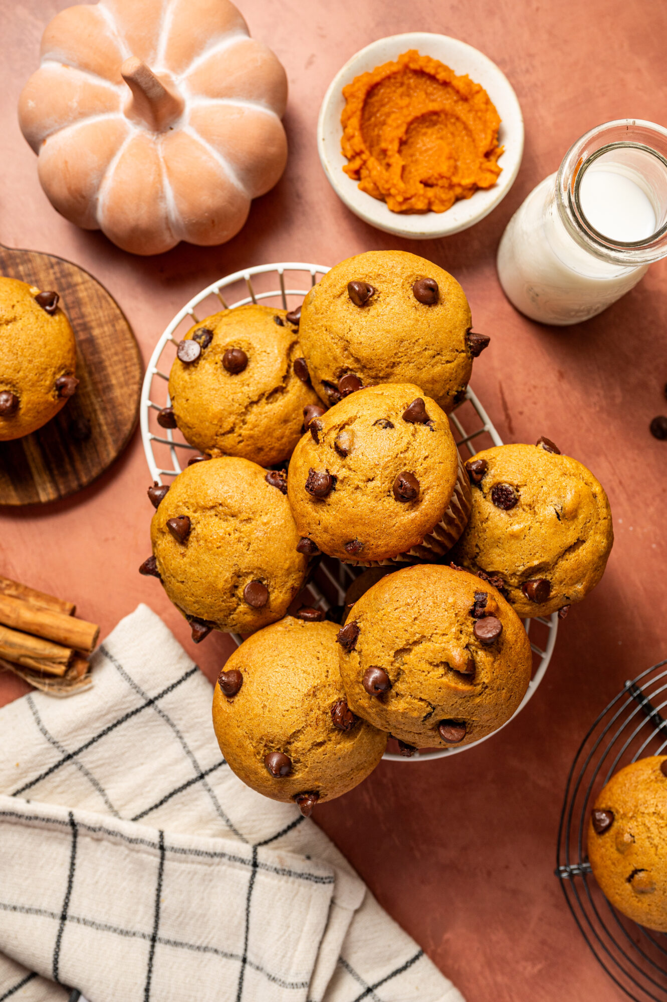 A basket of chocolate chip and pumpkin muffins surrounded by ingredients.