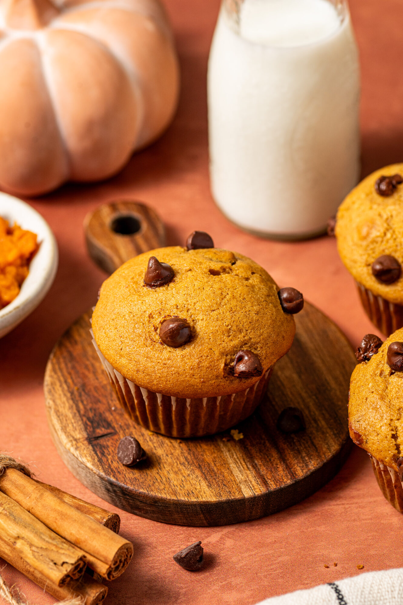 Pumpkin muffins with chocolate chips alongside a jar of milk and cinnamon sticks.