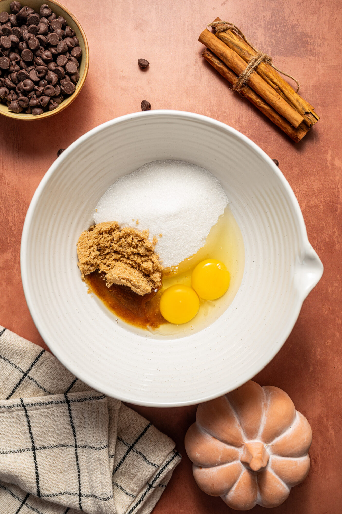 Granulated and brown sugar in a bowl with eggs and vanilla extract.