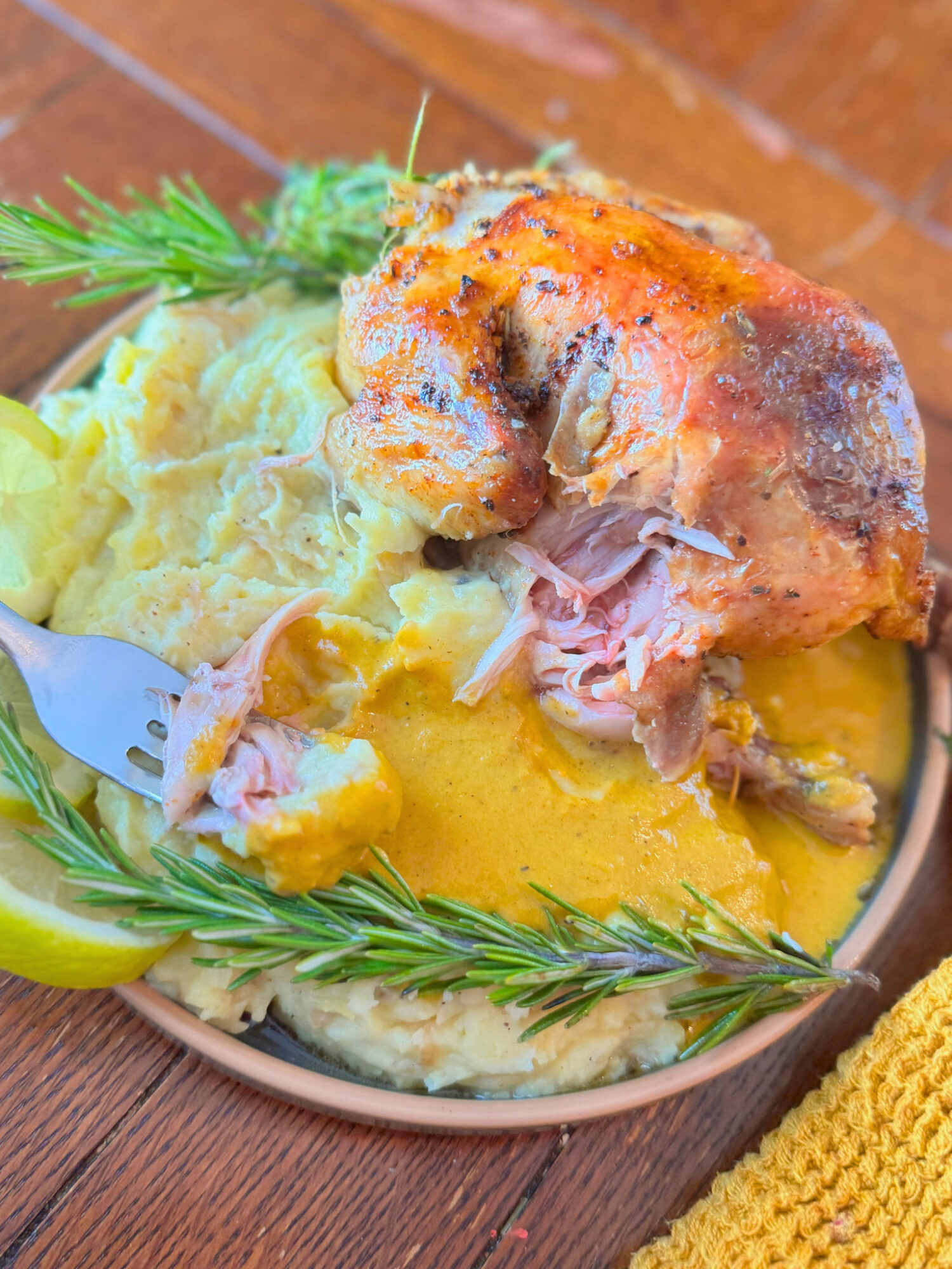 A serving of cornish hens on a plate with mashed potatoes and a fork.