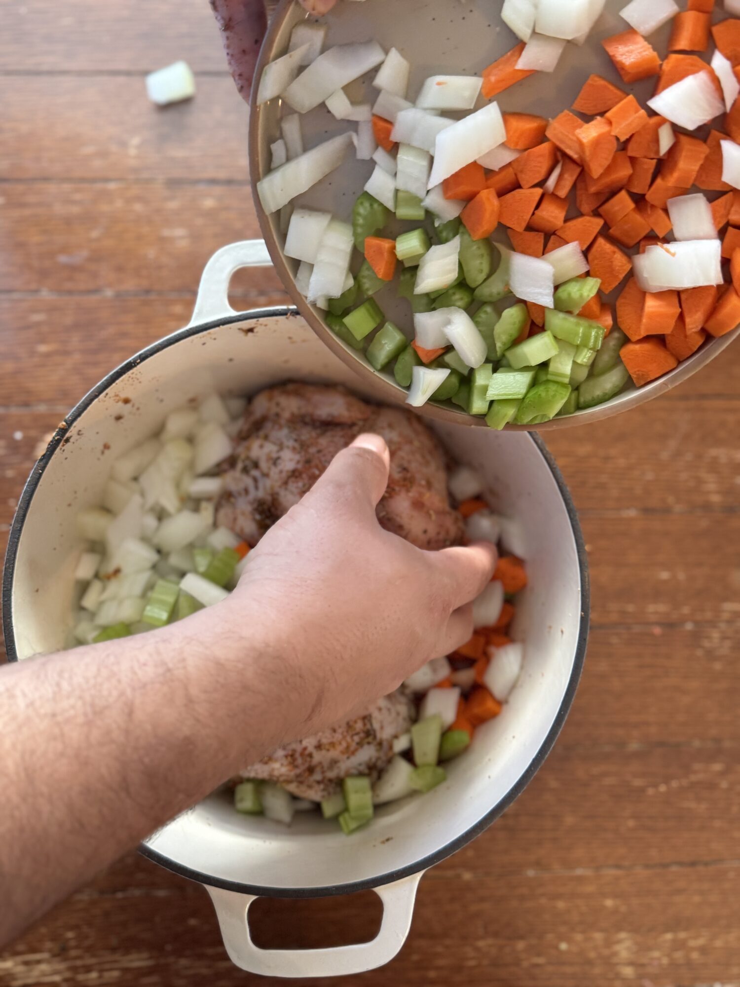 Adding chopped vegetables to a Dutch oven.