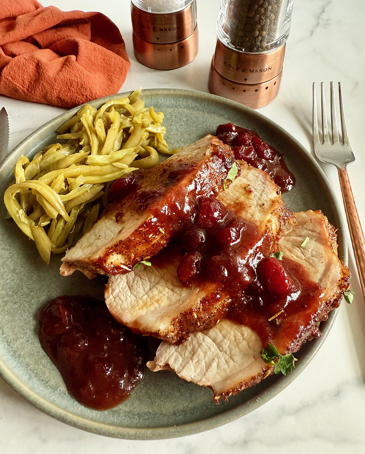 Cranberry balsamic pork loin roast served on a plate with green beans.