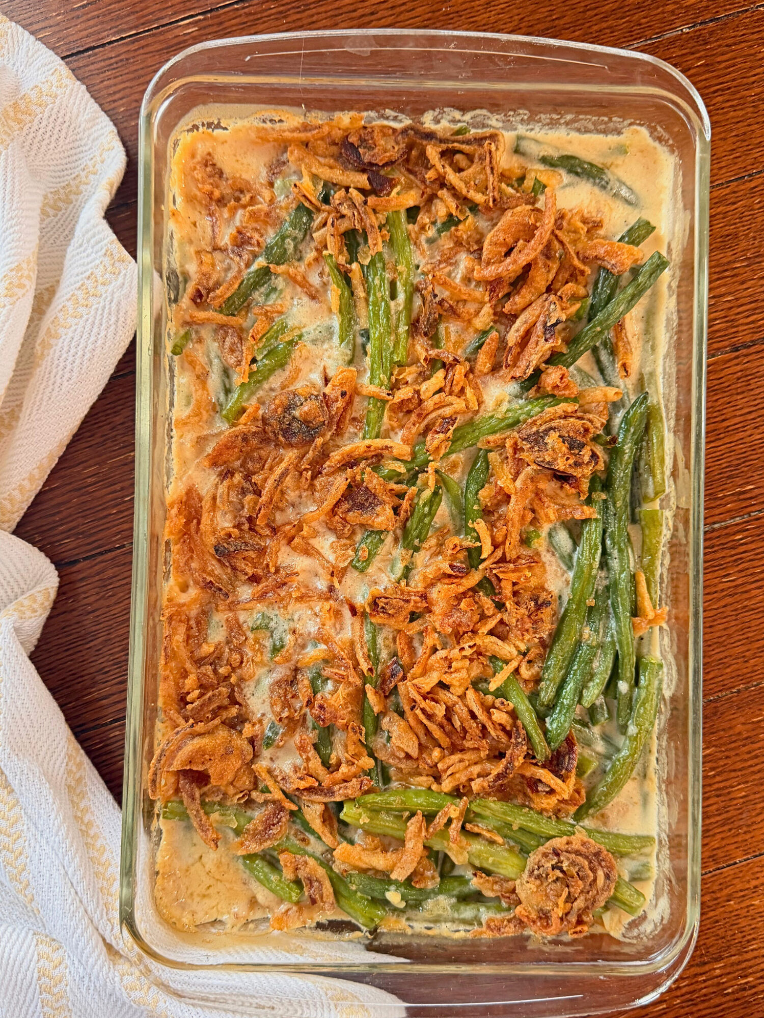Green bean casserole in a casserole dish over a wooden surface.