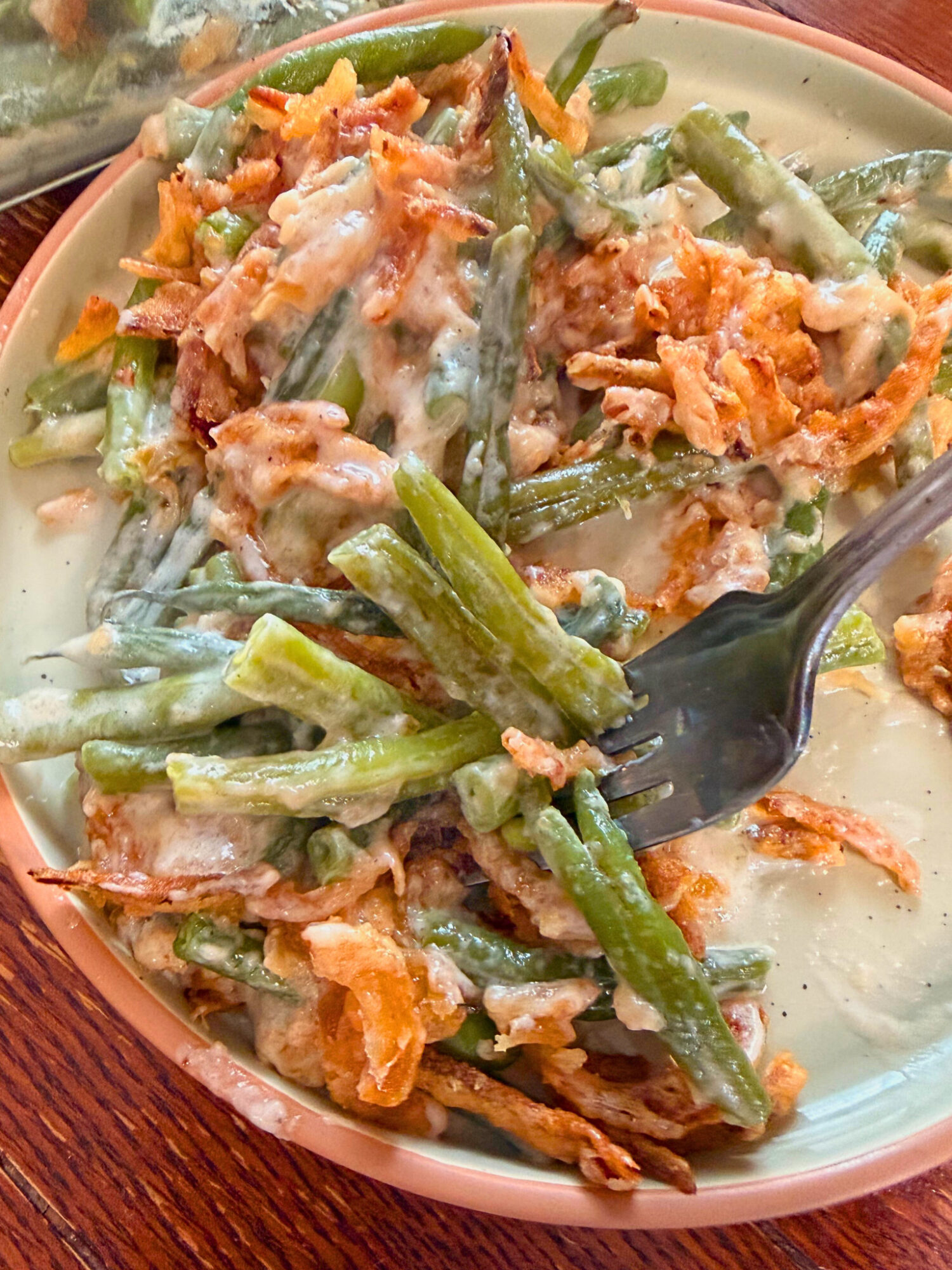 A fork digging into a bowl of green bean casserole.