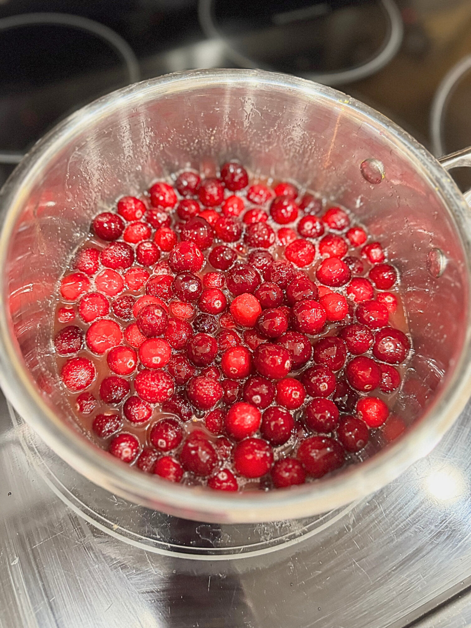 Cranberries cooking in a pot over the stove.