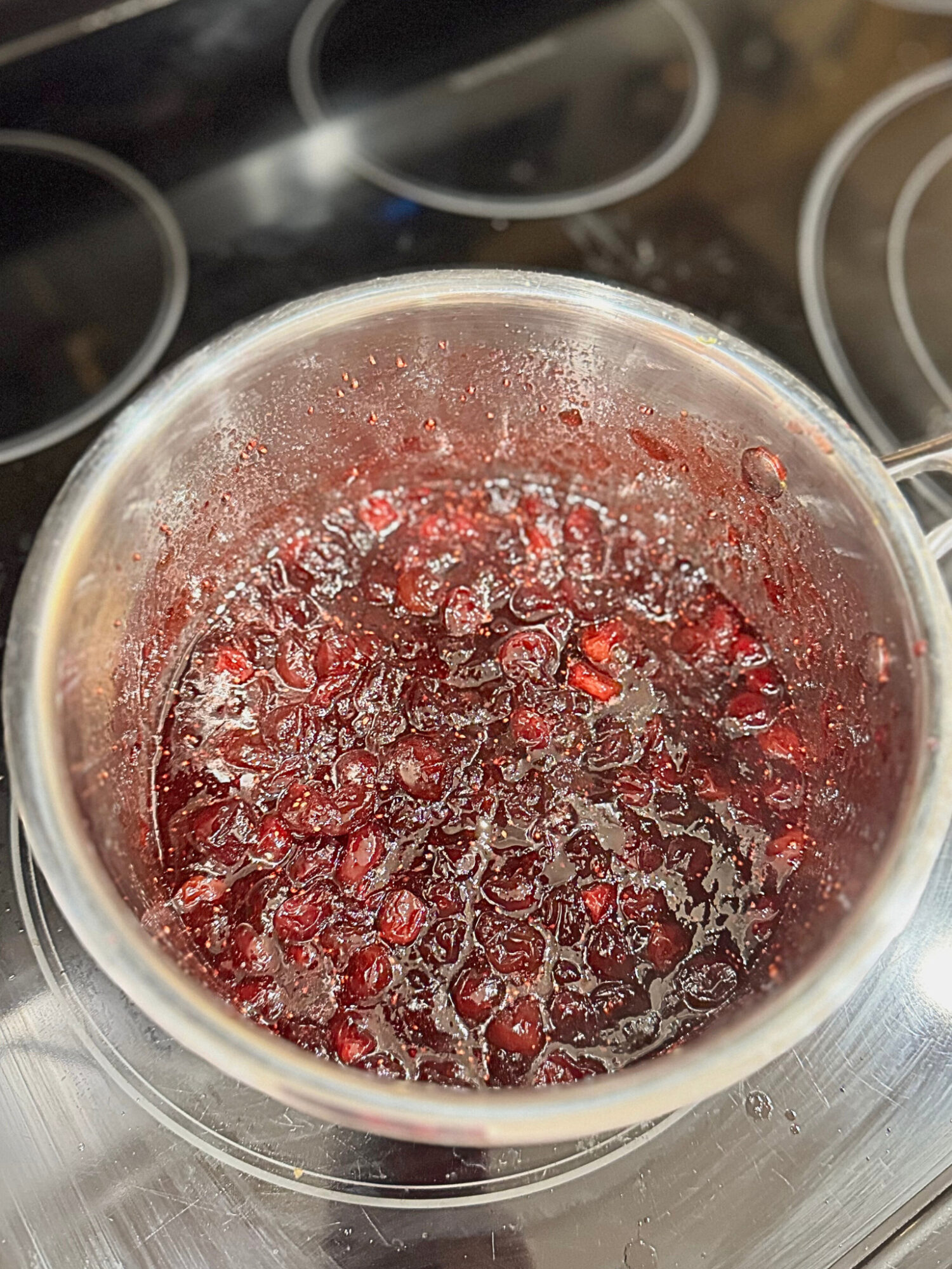 Homemade cranberry sauce in a pot over the stove.