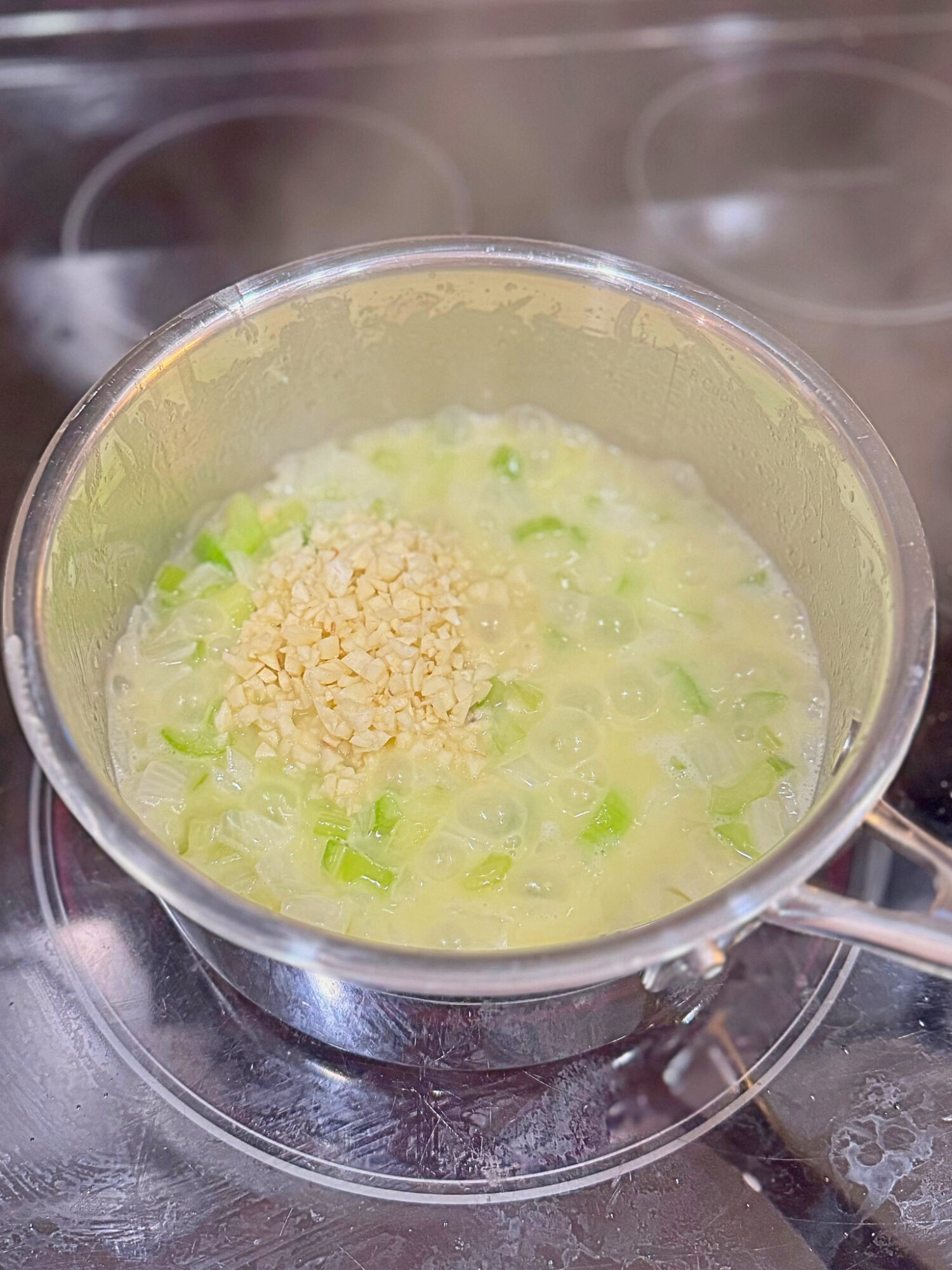 Wet ingredients for homemade stuffing simmering in a pot over the stove.