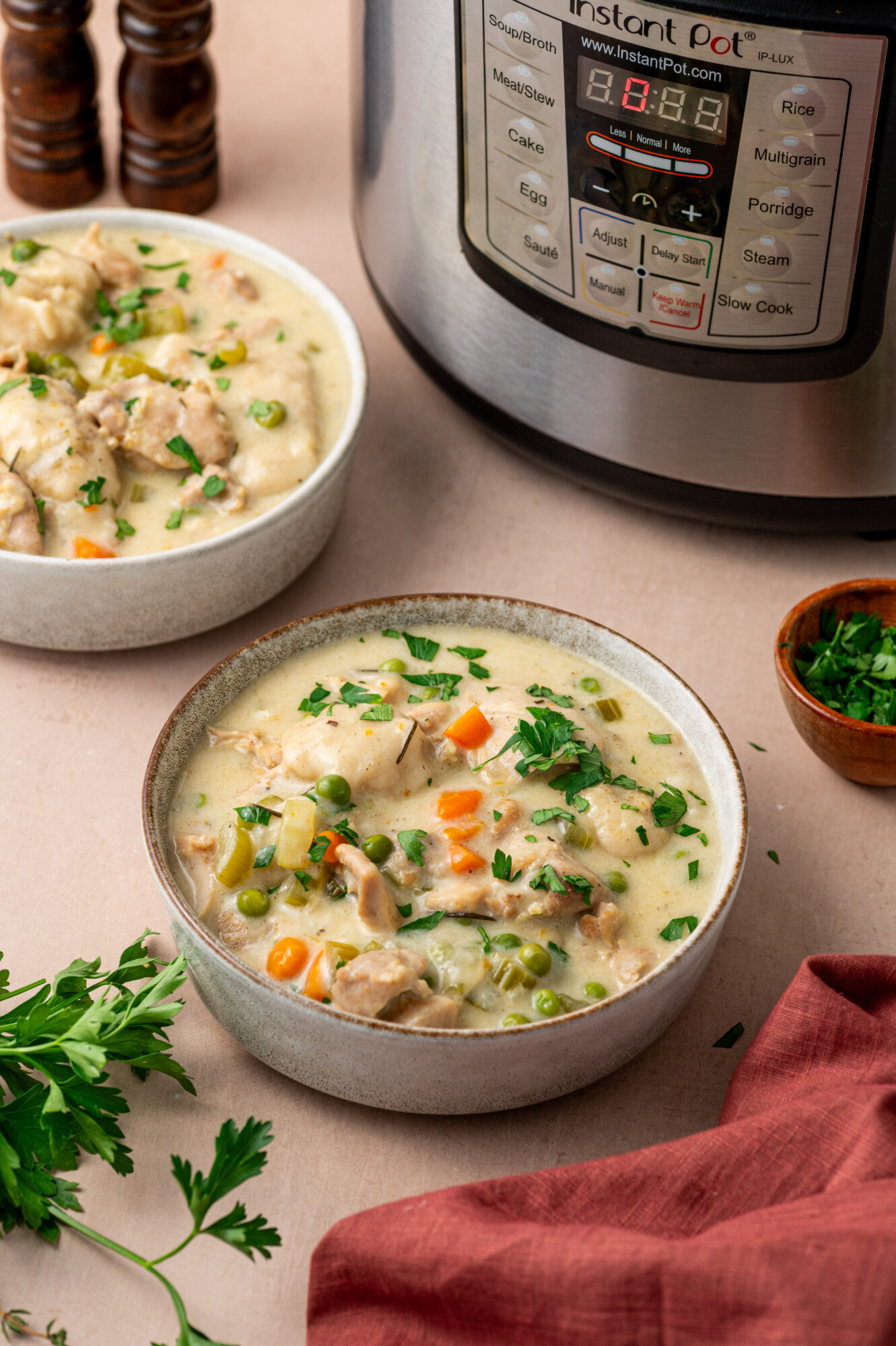 Two bowls of Instant Pot chicken and dumplings next to an Instant Pot.