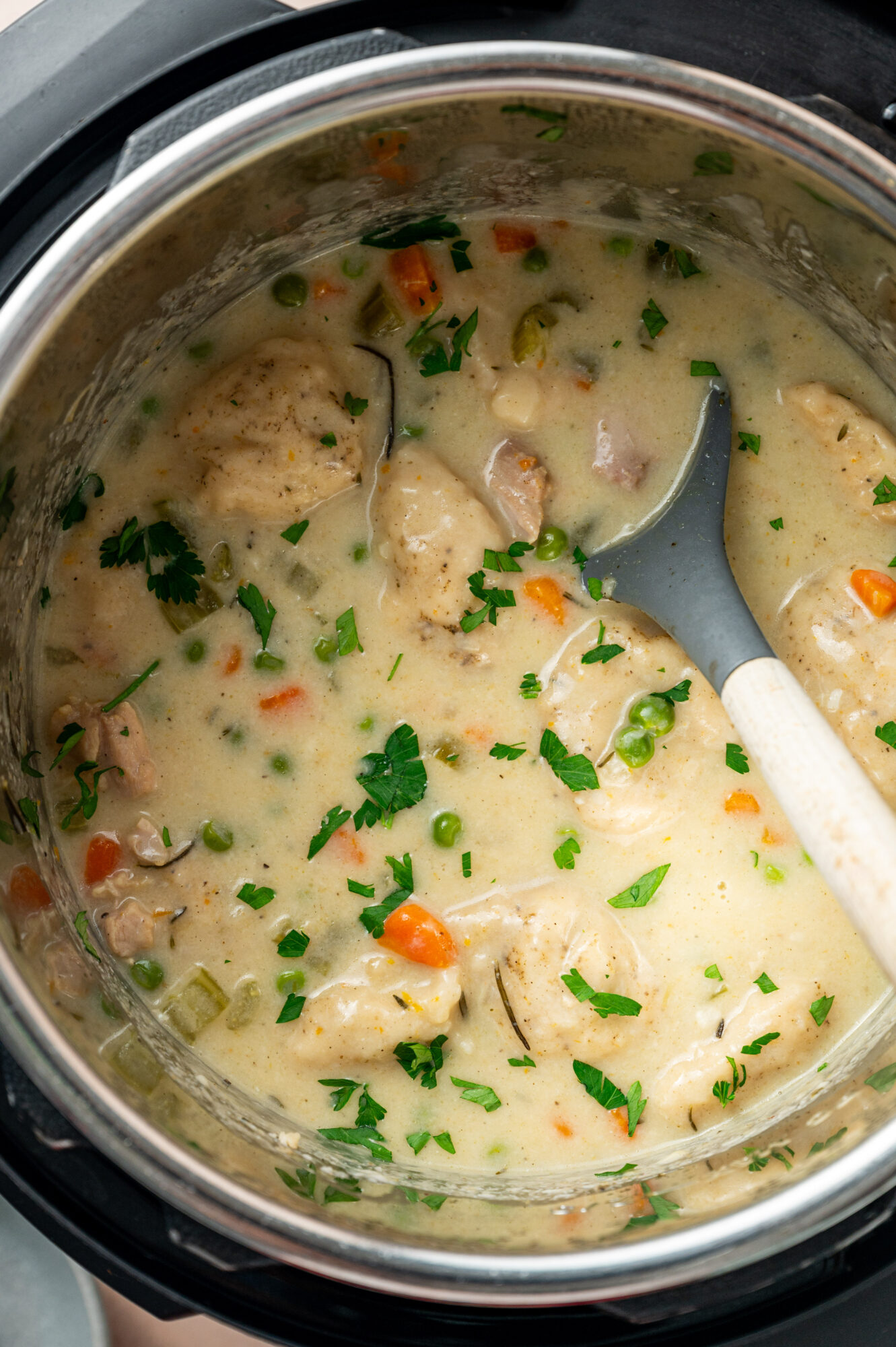 An Instant Pot of chicken and dumplings with a spoon.