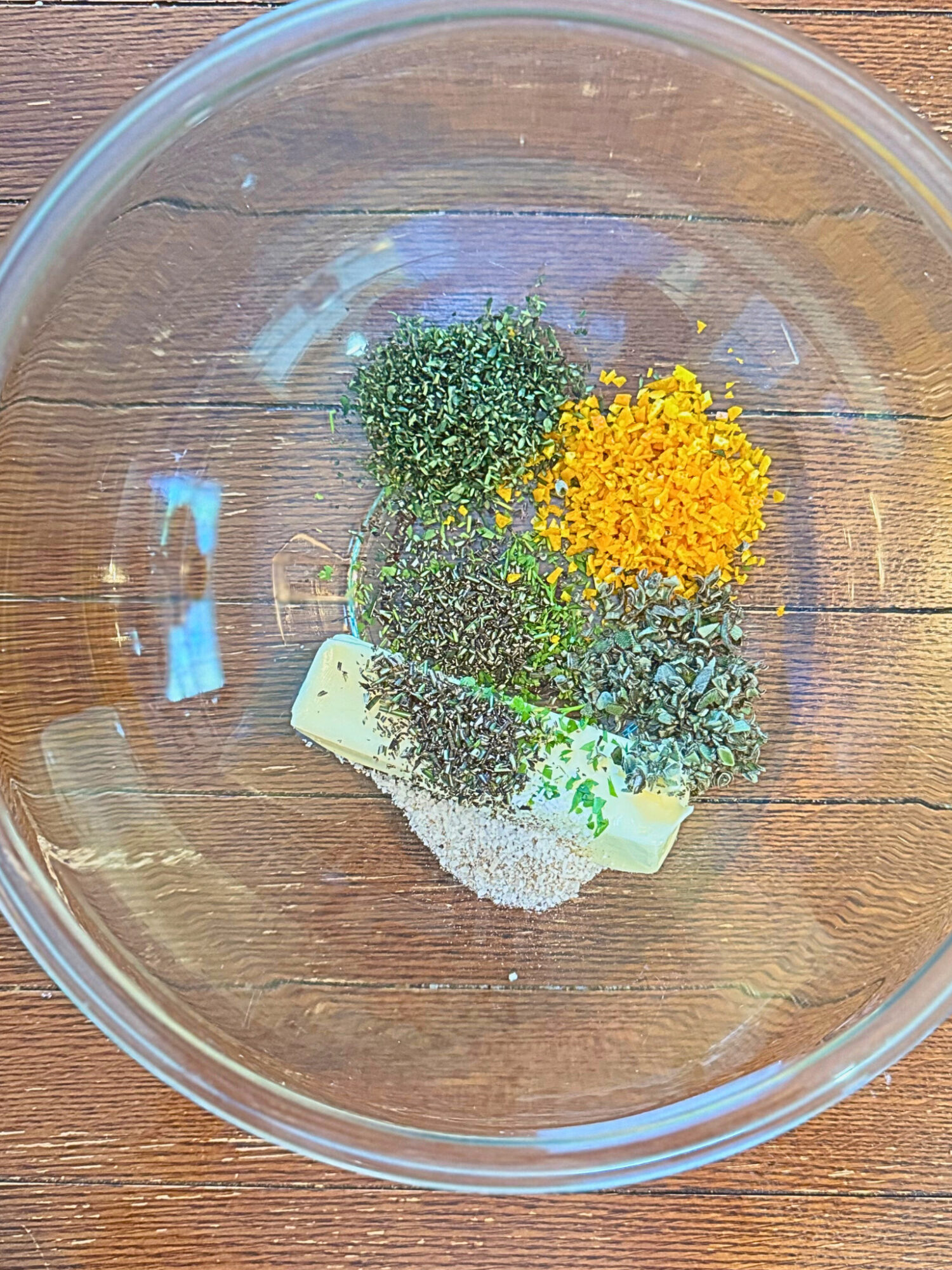 Seasonings for compound butter in a glass mixing bowl.