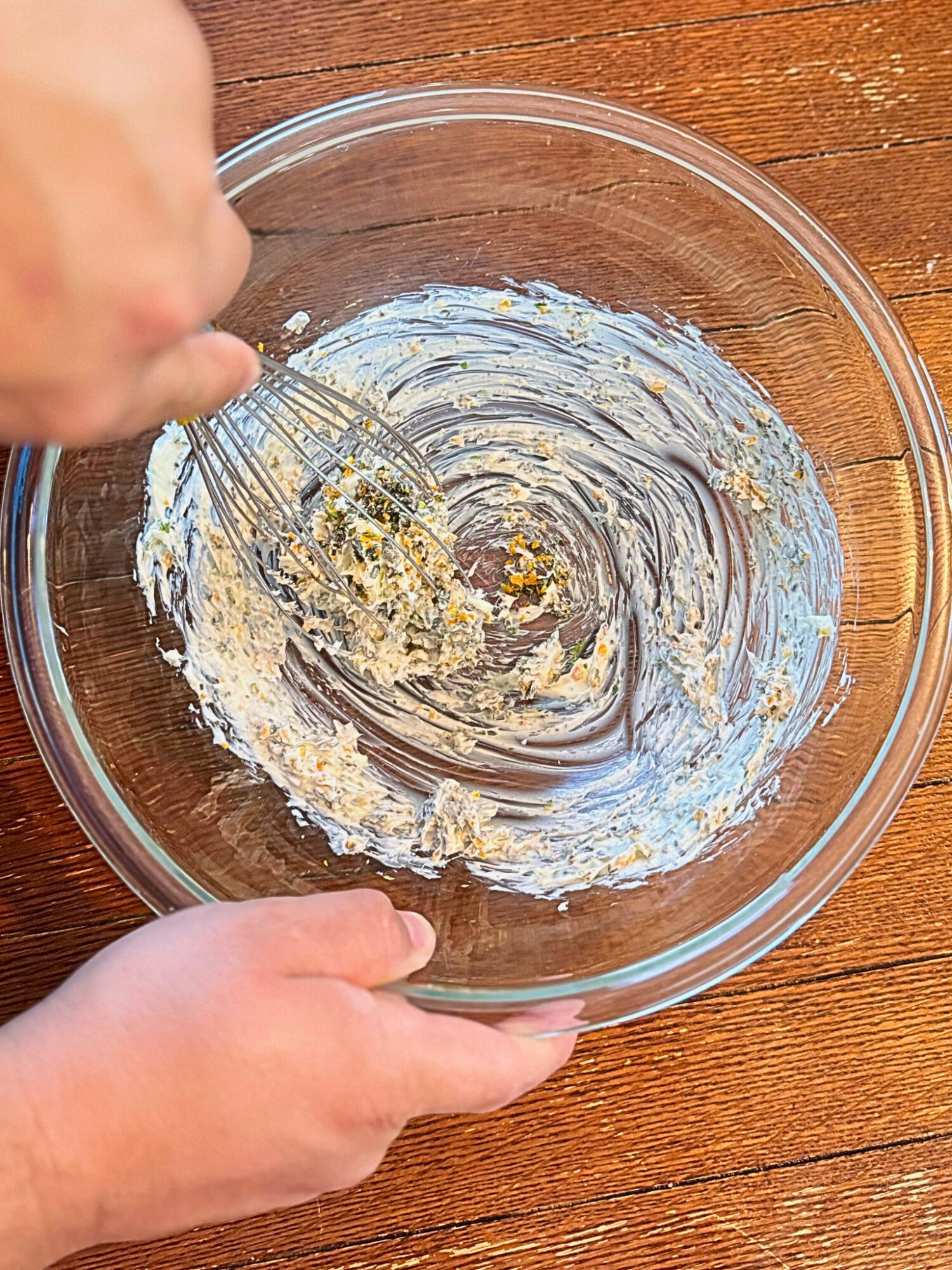 Whisking the compound butter in a glass mixing bowl.