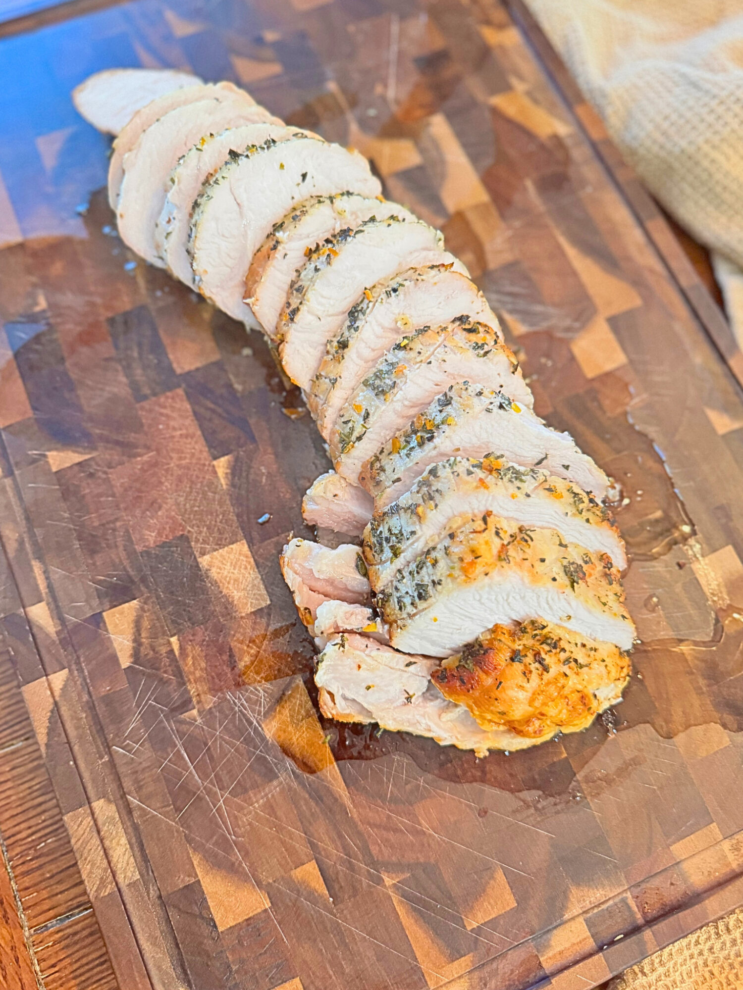 Slices of oven-roasted turkey breast on a wooden cutting board.
