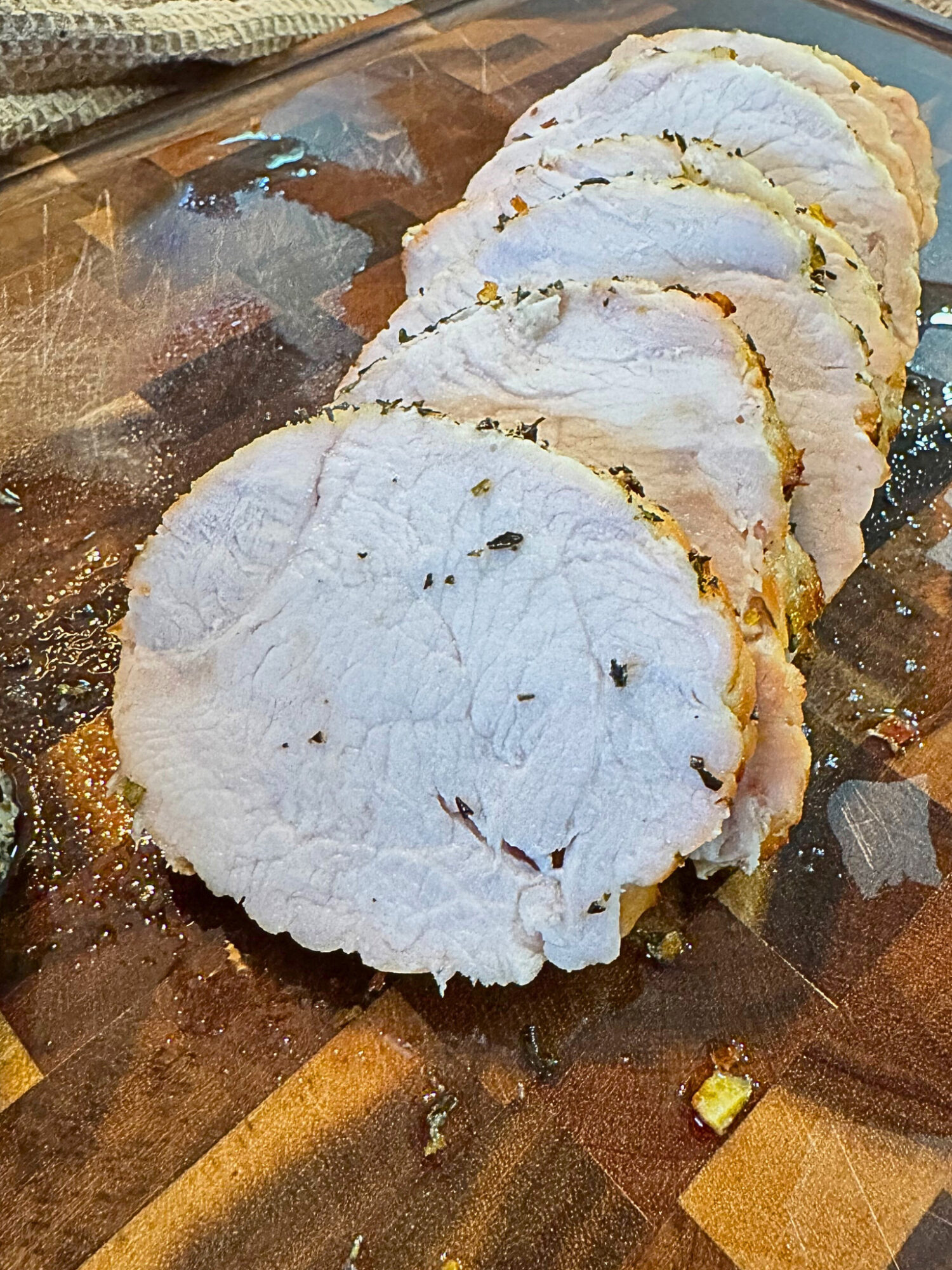 Close-up of sliced oven-roasted turkey breast on a wooden cutting board.