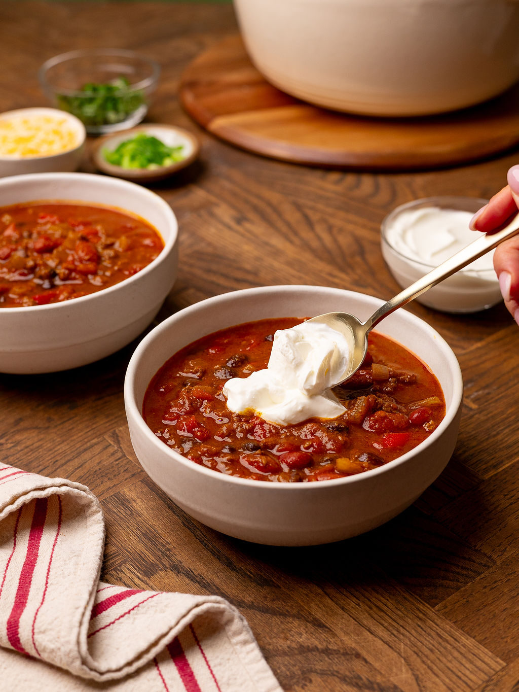 Adding sour cream to a bowl of pumpkin chili.