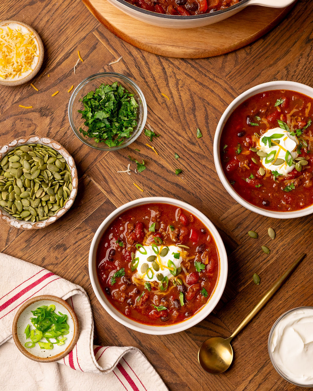 Aerial view of two bowls of pumpkin chili surrounded by ingredients.