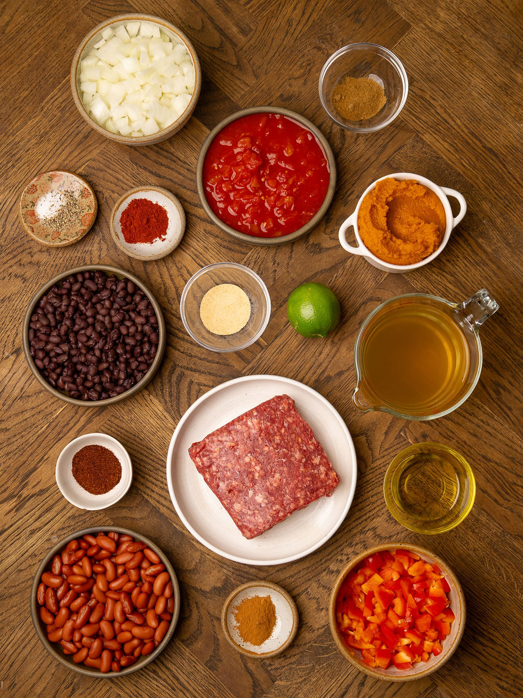 Ingredients for pumpkin chili over a wooden surface.
