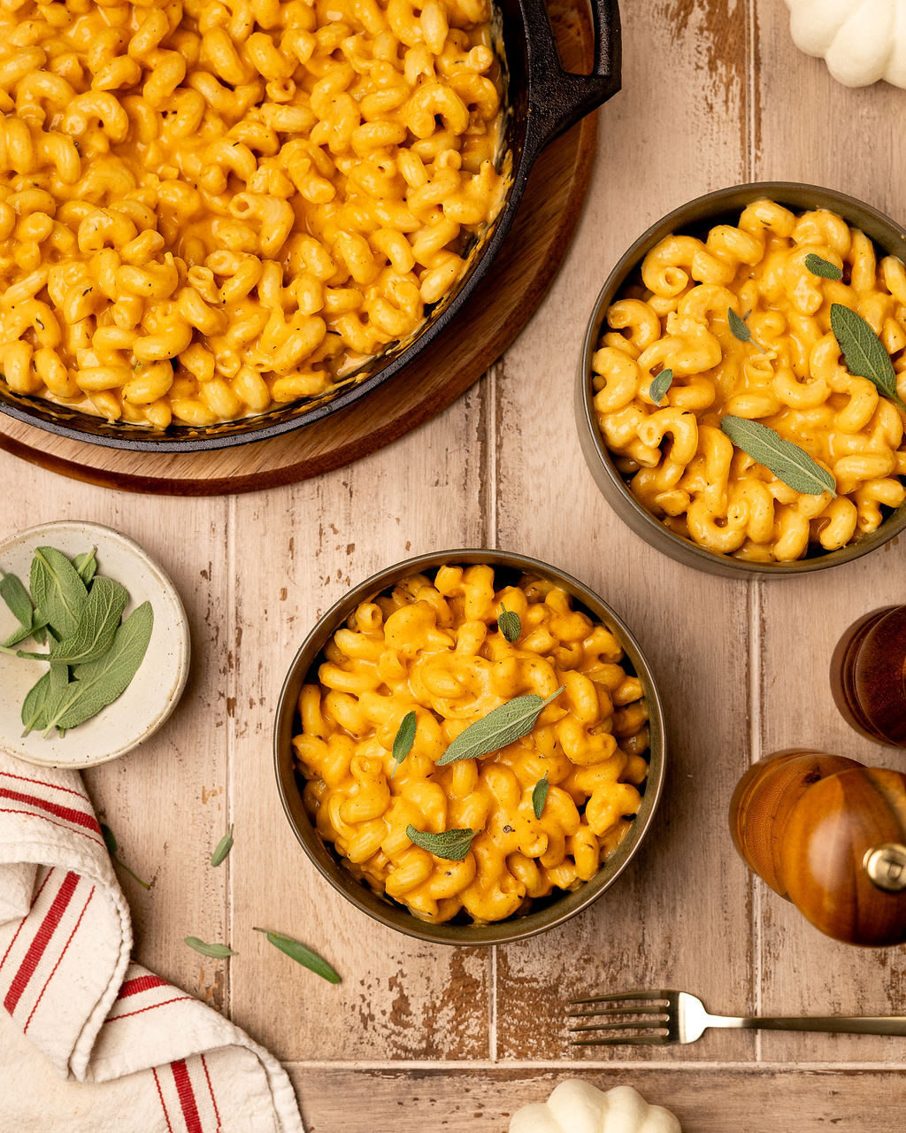 Two servings of pumpkin mac and cheese next to a pan full of more mac.