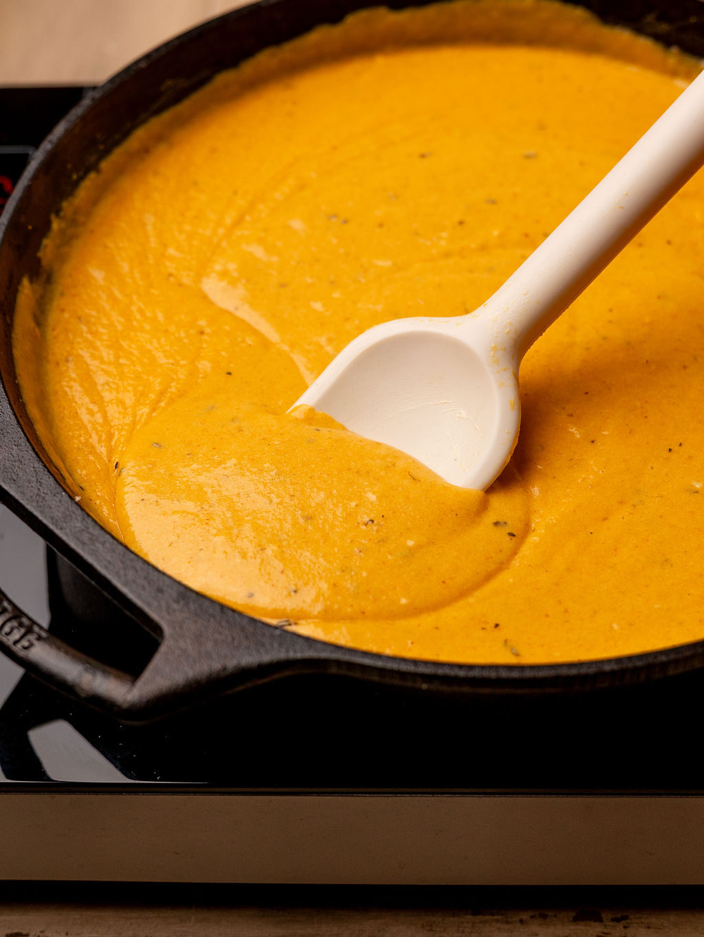 Mixing cheese sauce in a cast iron pan.