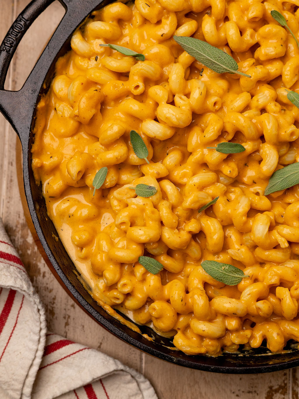Pumpkin mac and cheese garnished with sage leaves in a cast iron pan.