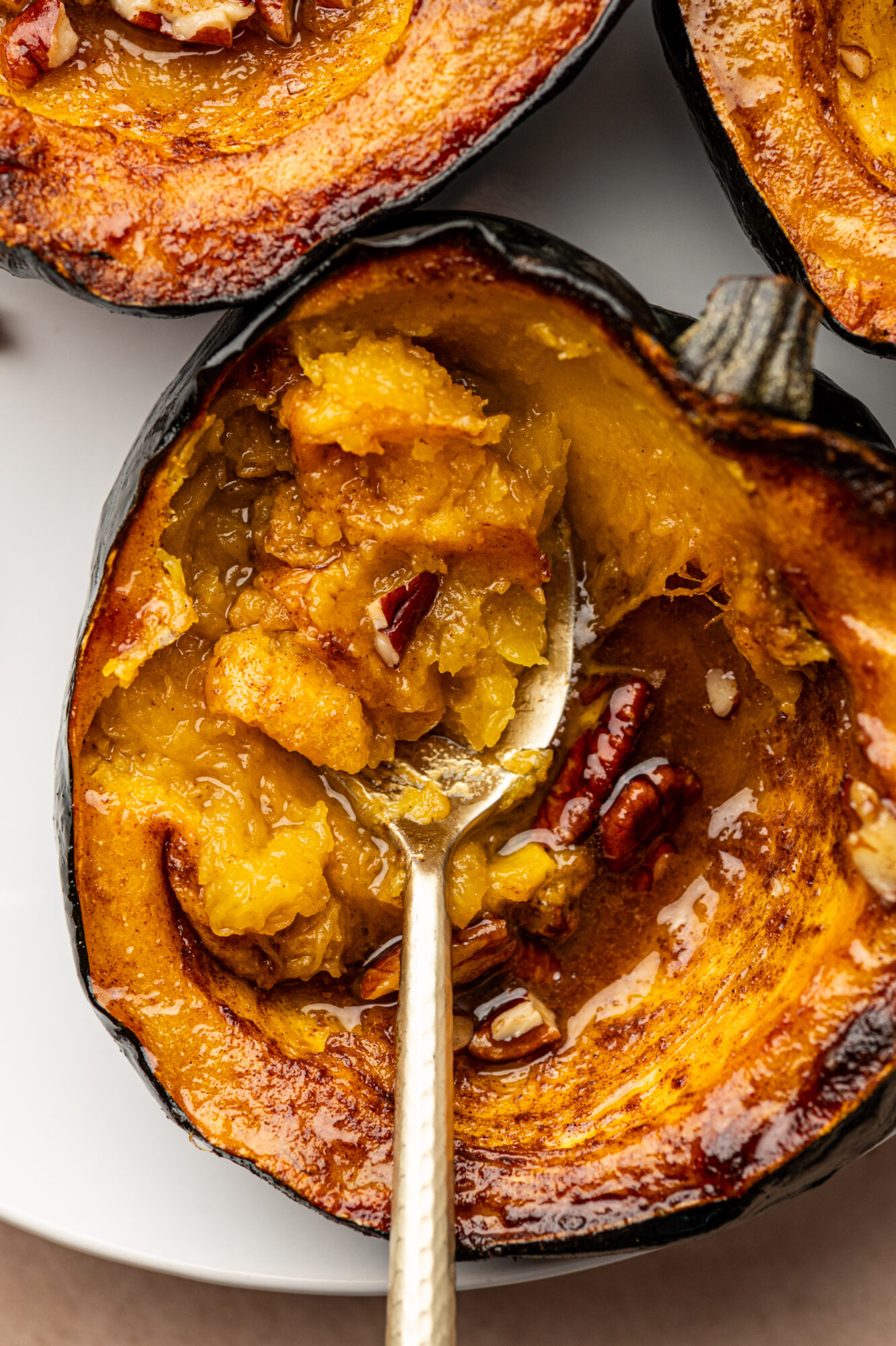 A spoon taking a scoop out of a roasted acorn squash.