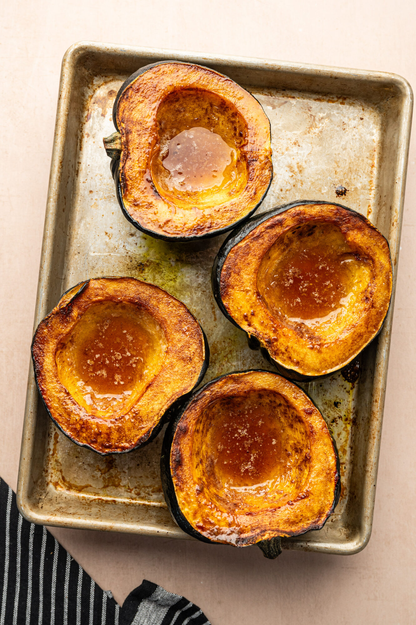 Roasted acorn squash on a pan with brown butter.
