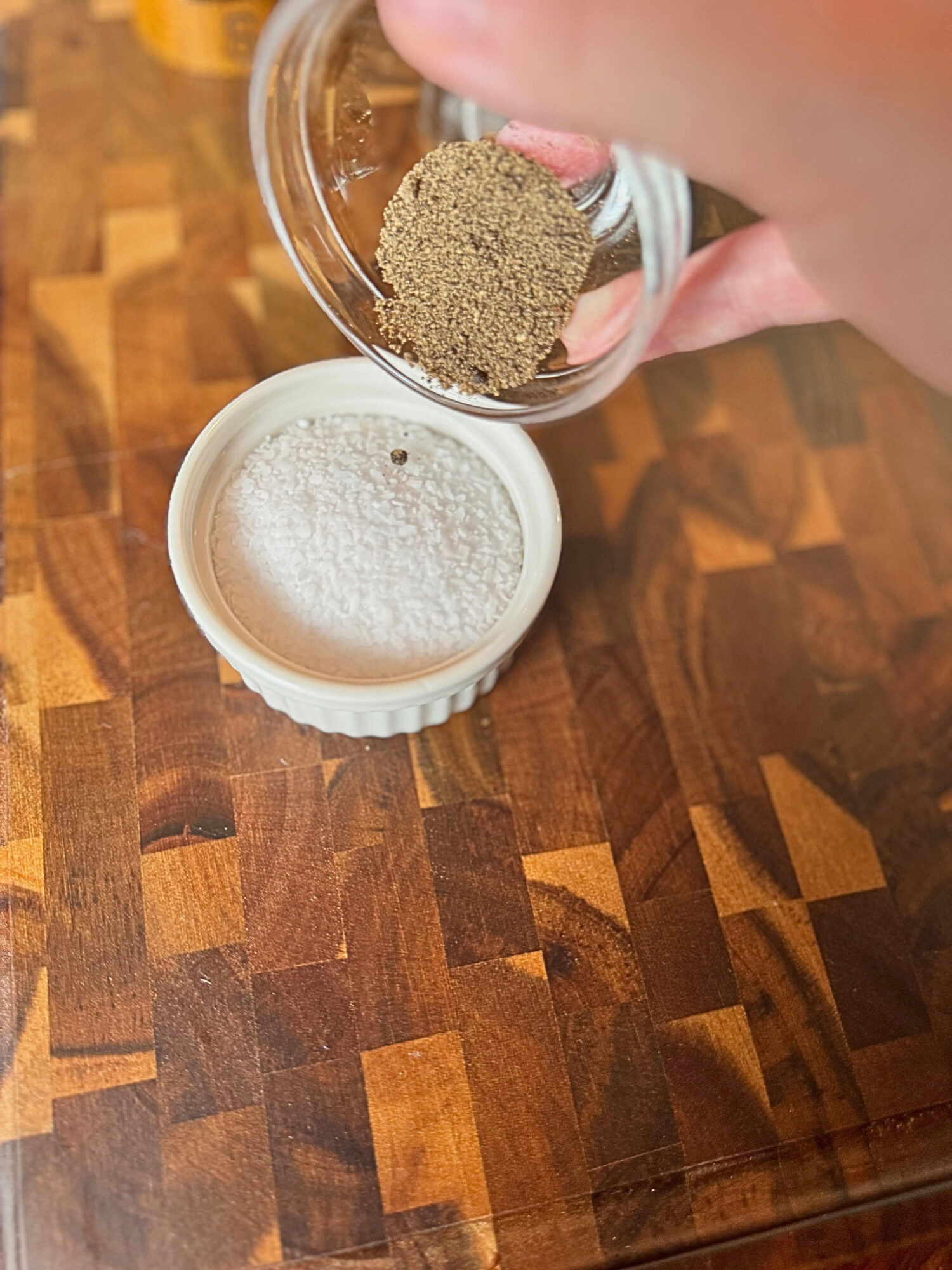 Adding freshly ground pepper to a shallow dish of salt.