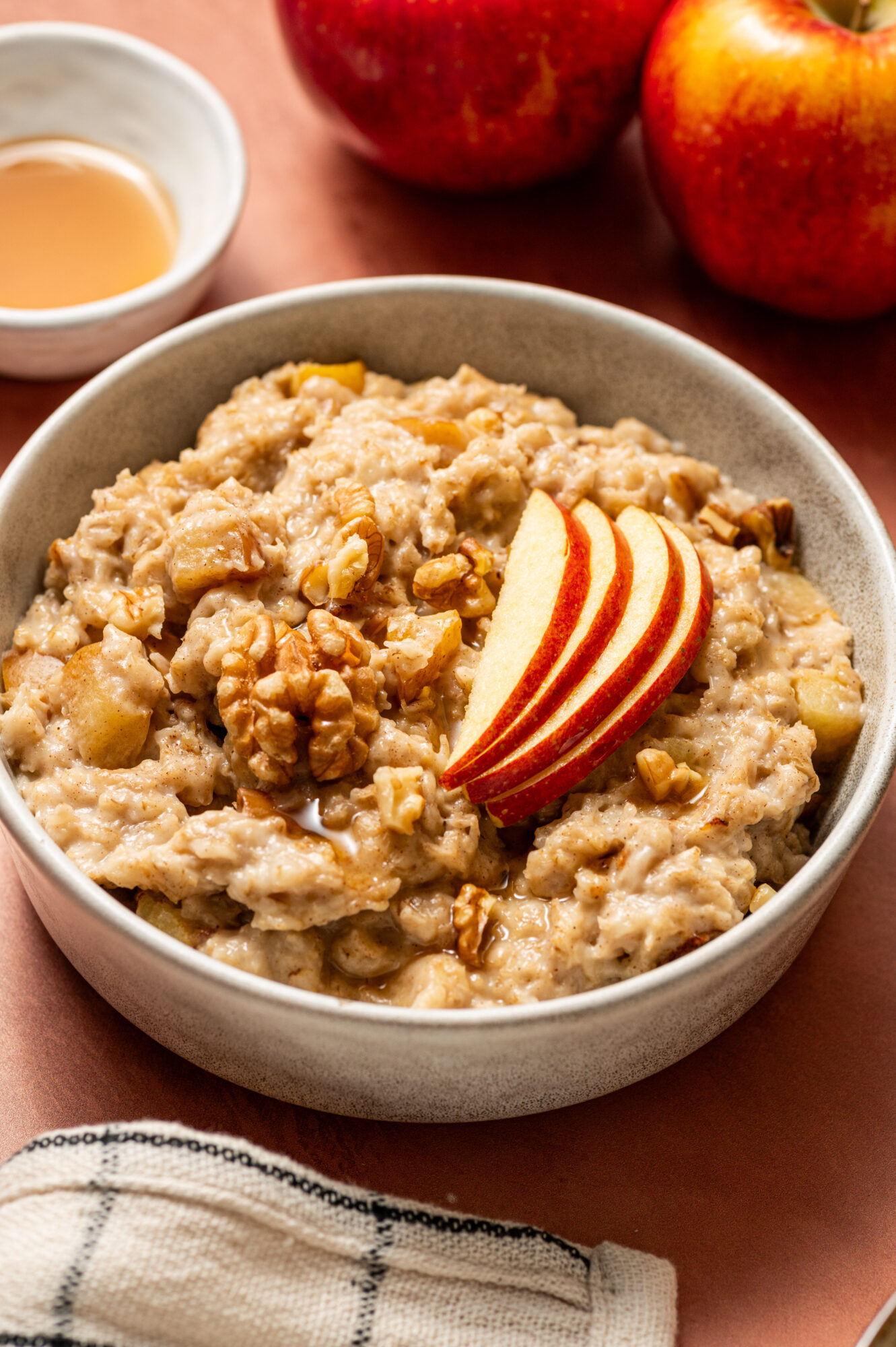 Apple cinnamon oatmeal in a white bowl topped with apple slices.