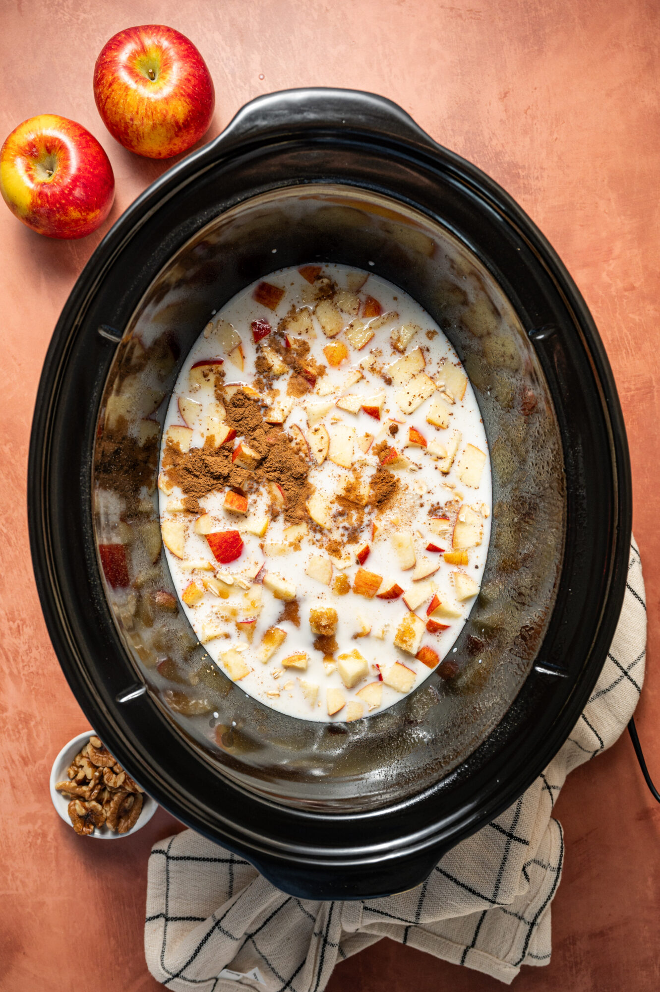 Ingredients for apple cinnamon oatmeal in a slow cooker ready to cook.