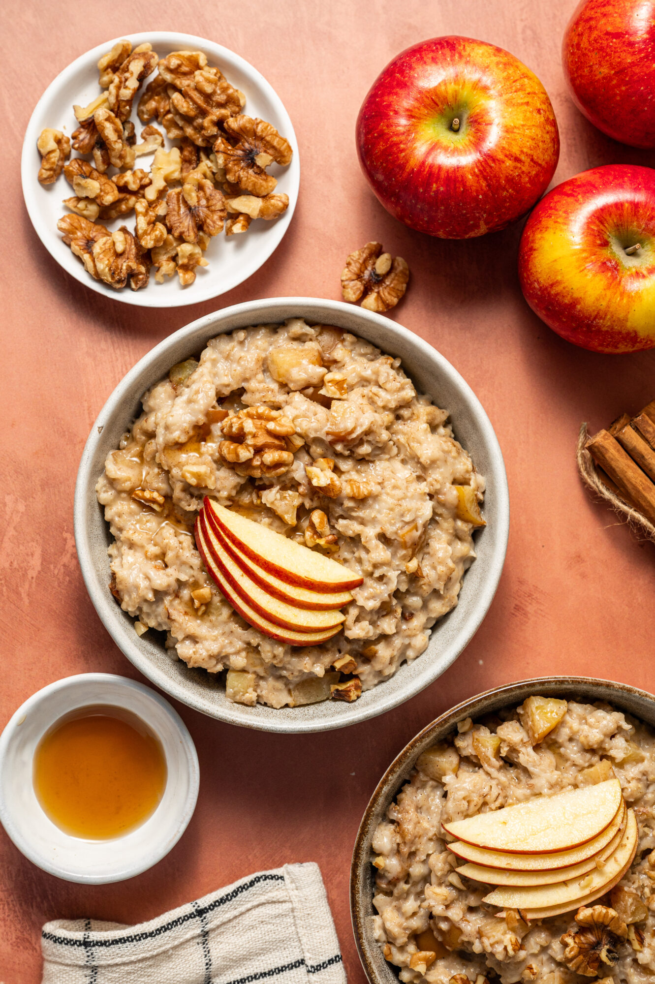 Bowls of apple cinnamon oatmeal surrounded by ingredients.