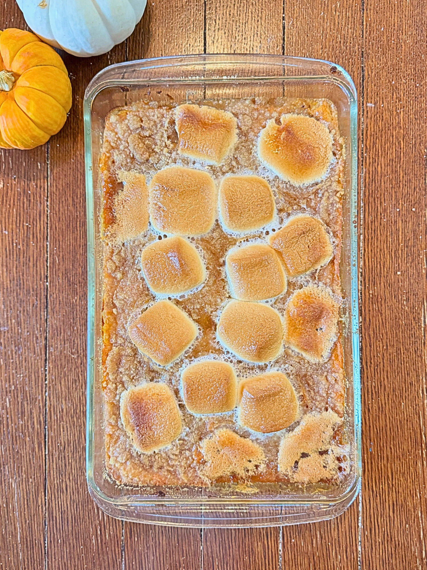 Sweet potato casserole in a casserole dish on a wooden table.