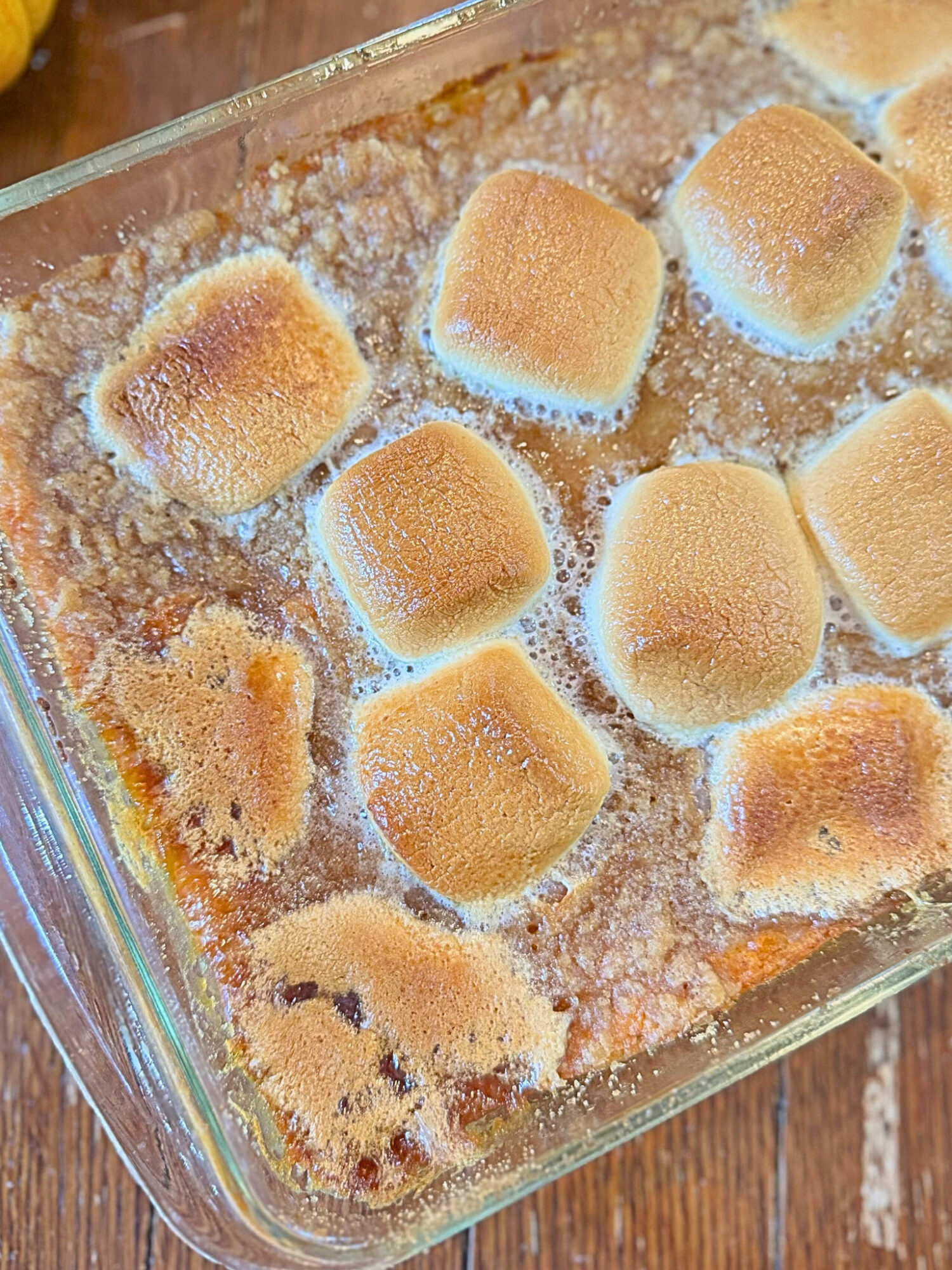Close-up of sweet potato casserole in a casserole dish over a wooden table.