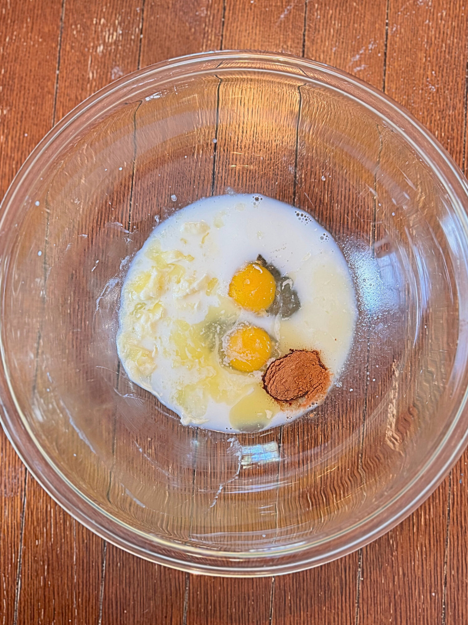 Wet ingredients for sweet potato casserole in a glass mixing bowl.