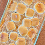 Sweet potato casserole in a casserole dish on a wooden table.