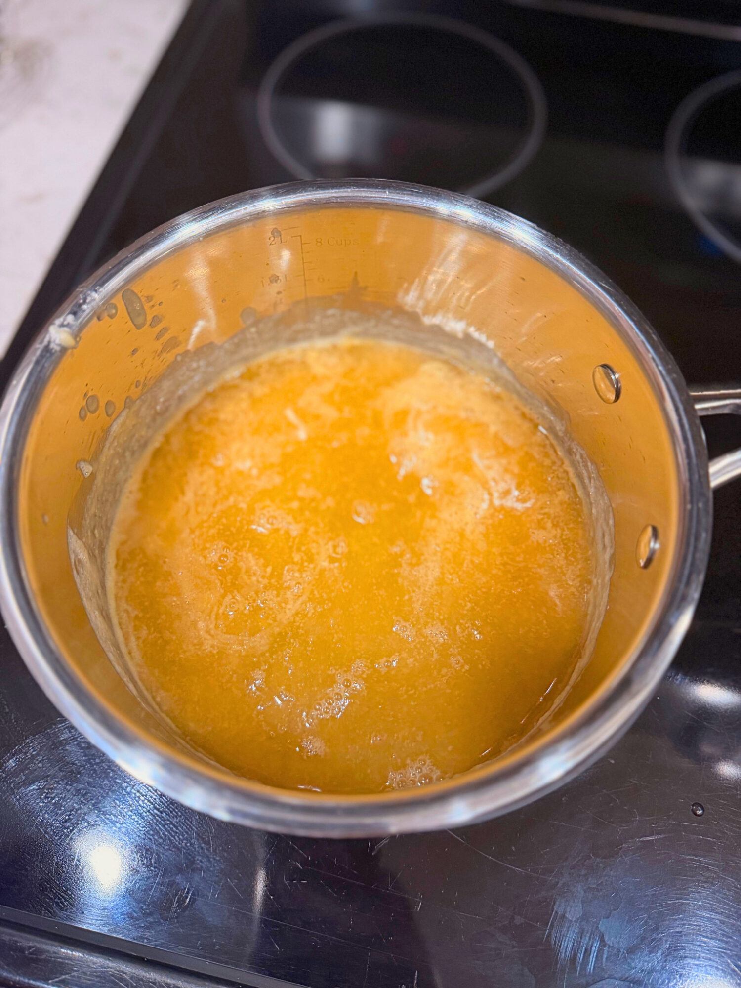 Melted butter and chicken stock in a pot over a stove top.