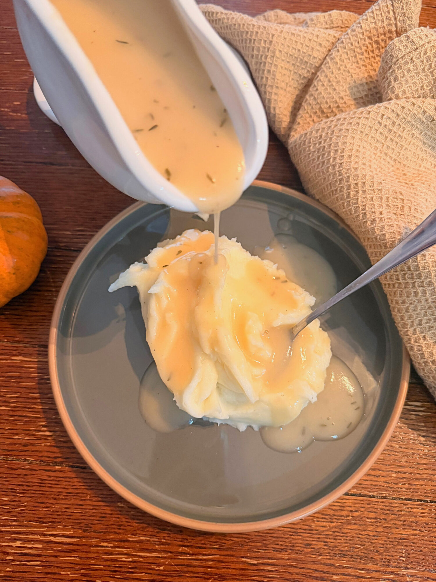 Pouring turkey gravy on a plate of mashed potatoes.