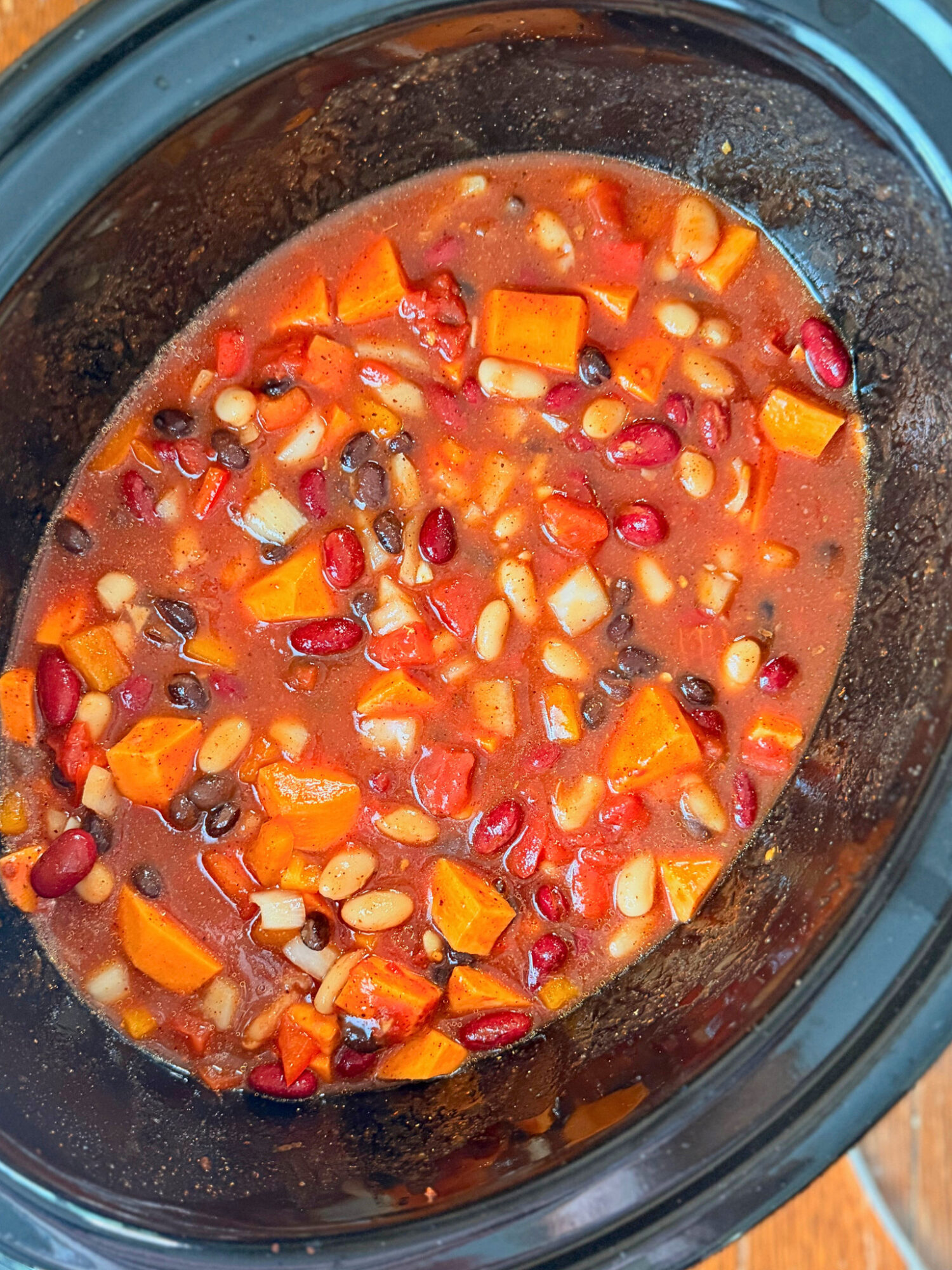 A slow cooker full of chili ready to cook.