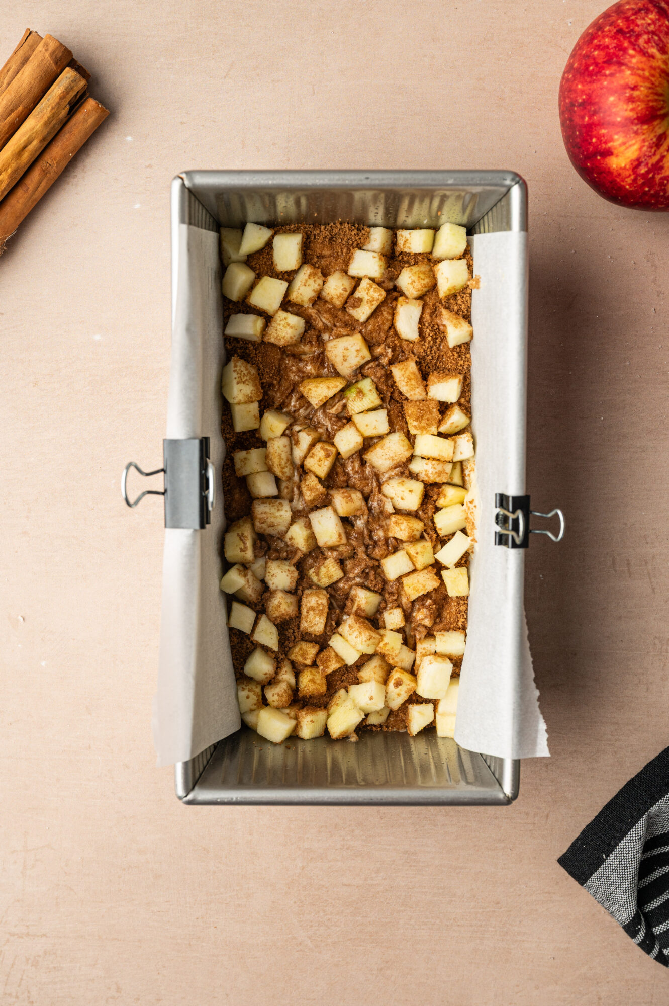 Adding layers of diced apples to a loaf pan for apple cinnamon bread.