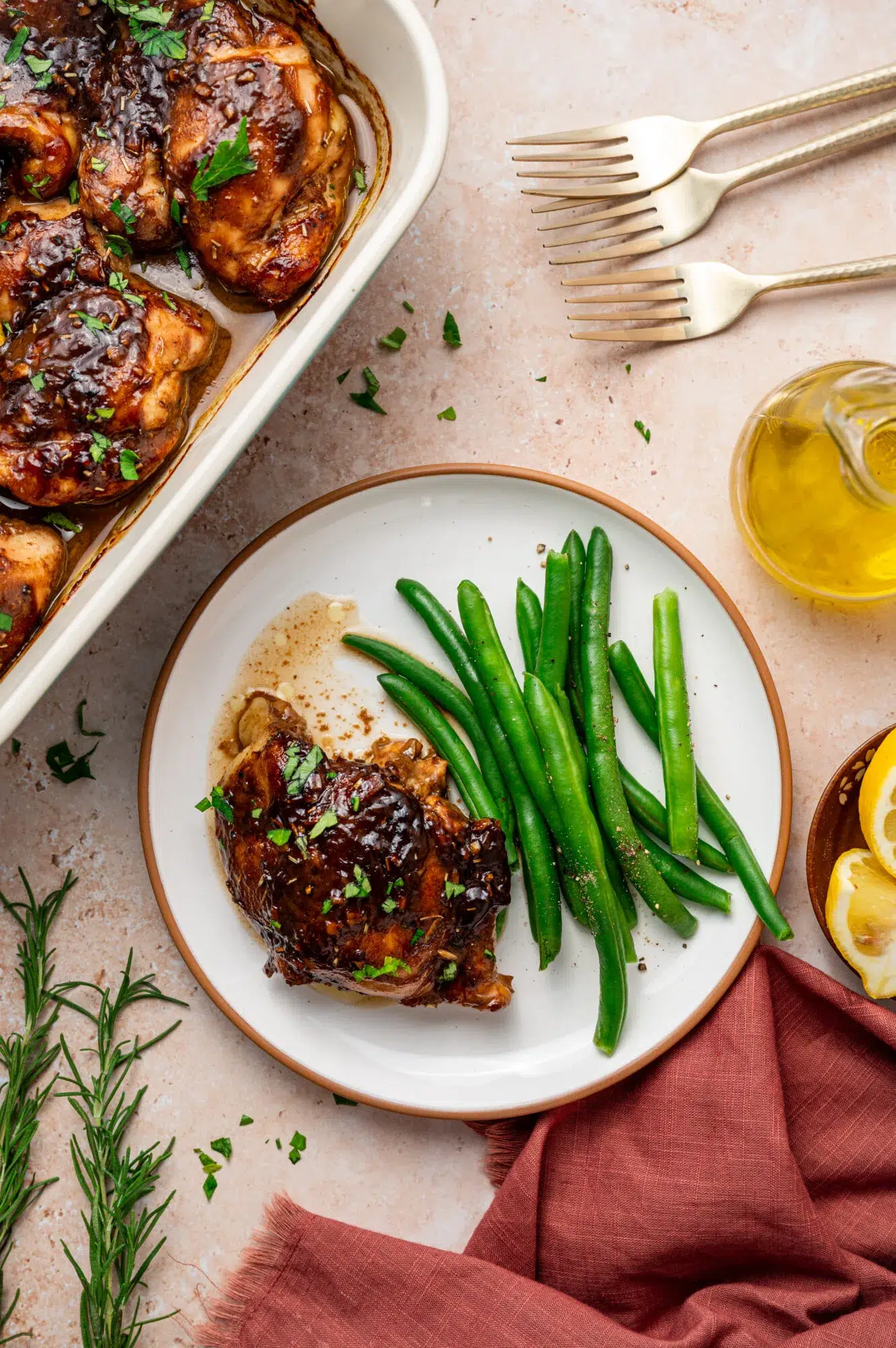 Balsamic Dijon mustard chicken thighs on a white plate with a side of green beans.